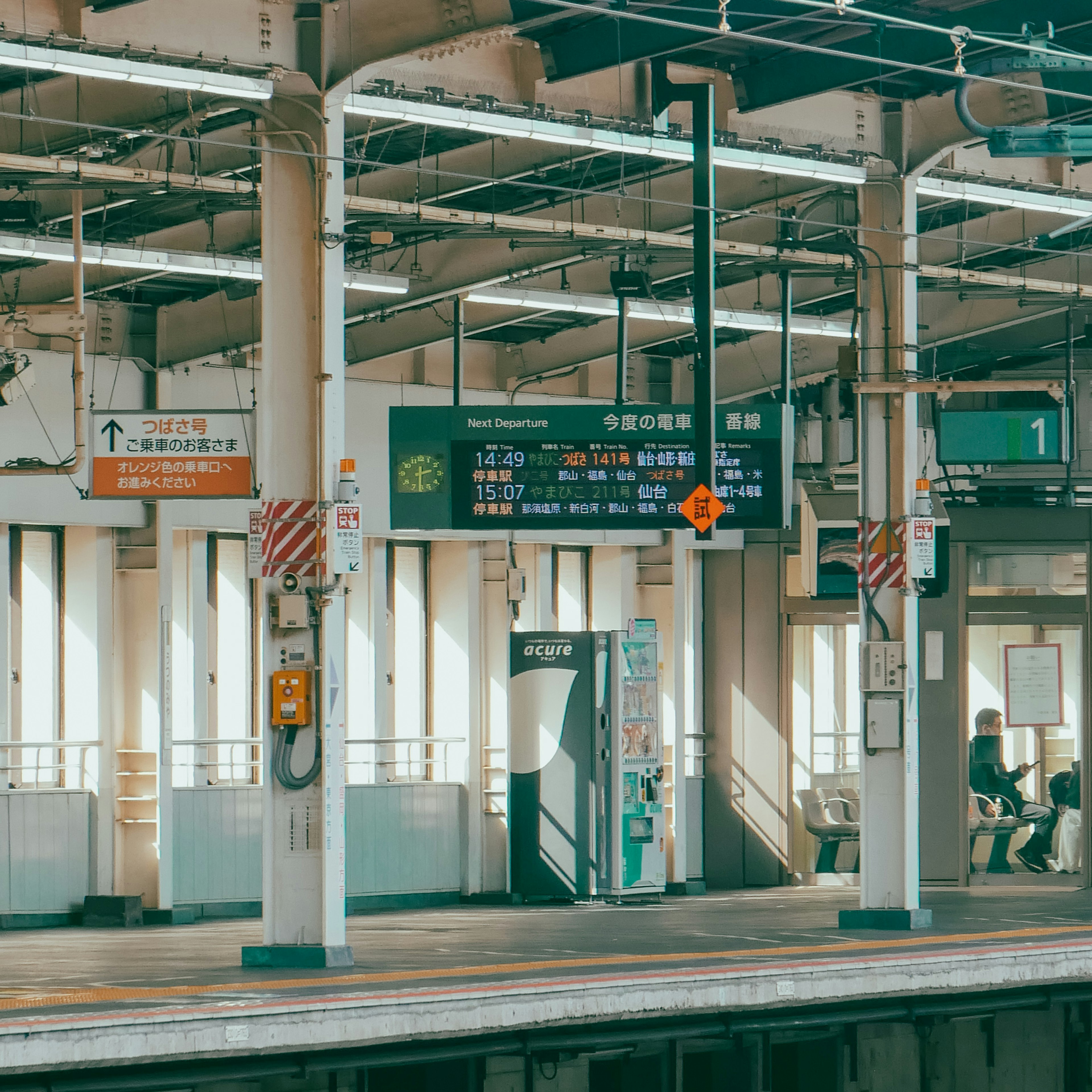 Platform view with information board and seating at a train station