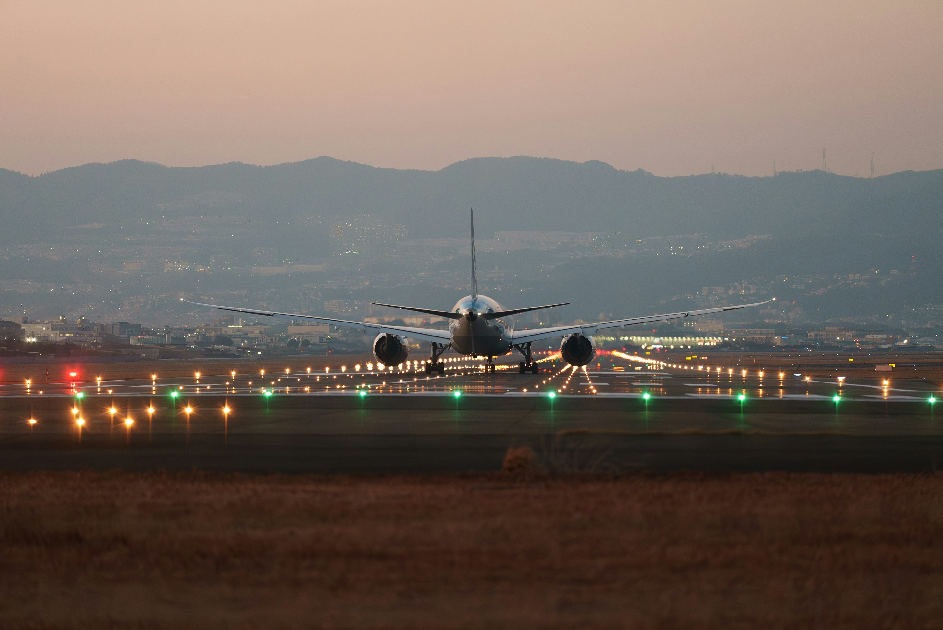 Aircraft landing on runway with sunset backdrop