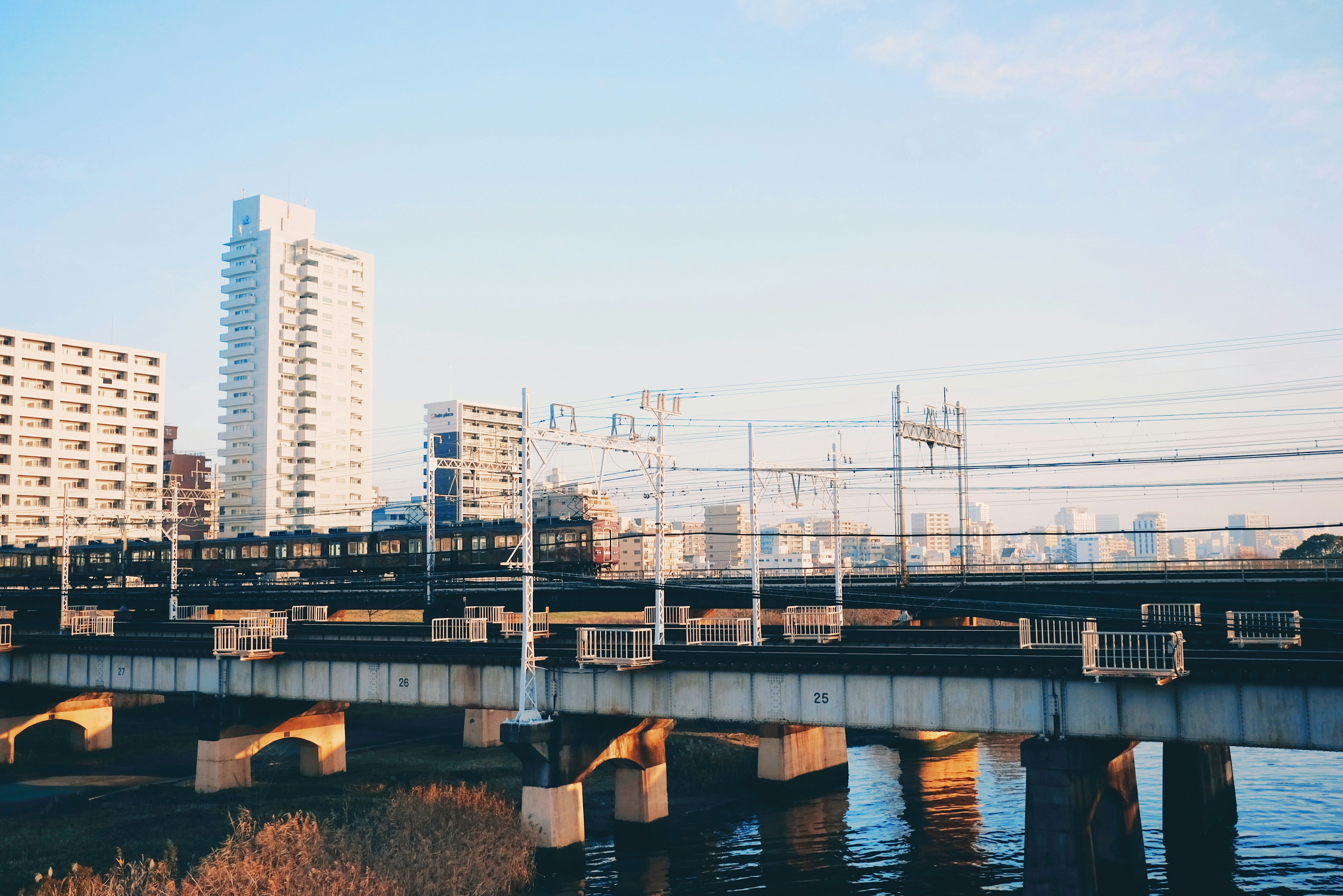 ทิวทัศน์เมืองที่มีสะพานรถไฟข้ามแม่น้ำและอาคารในพื้นหลัง