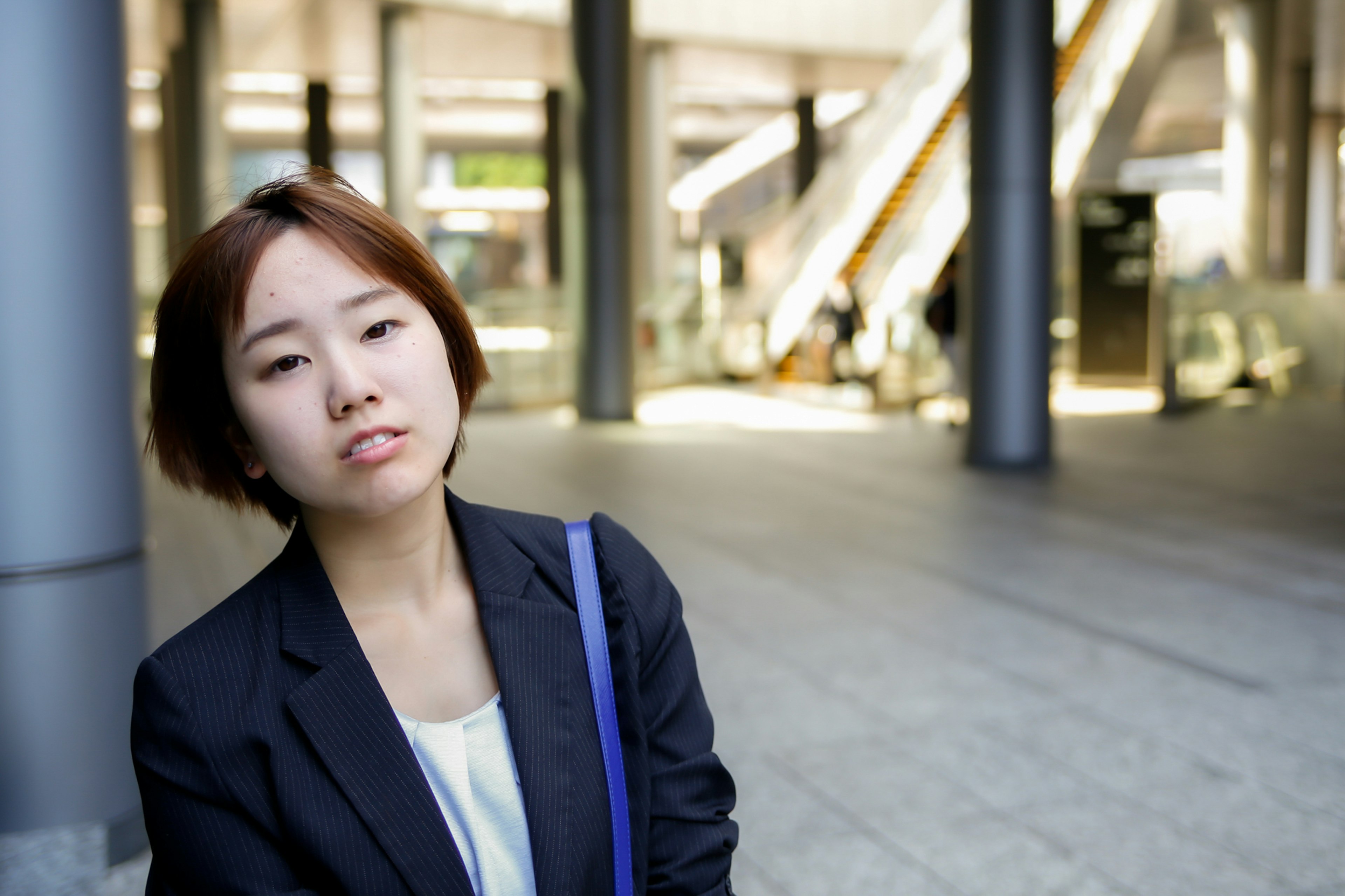 A young woman in a business suit poses against an urban background