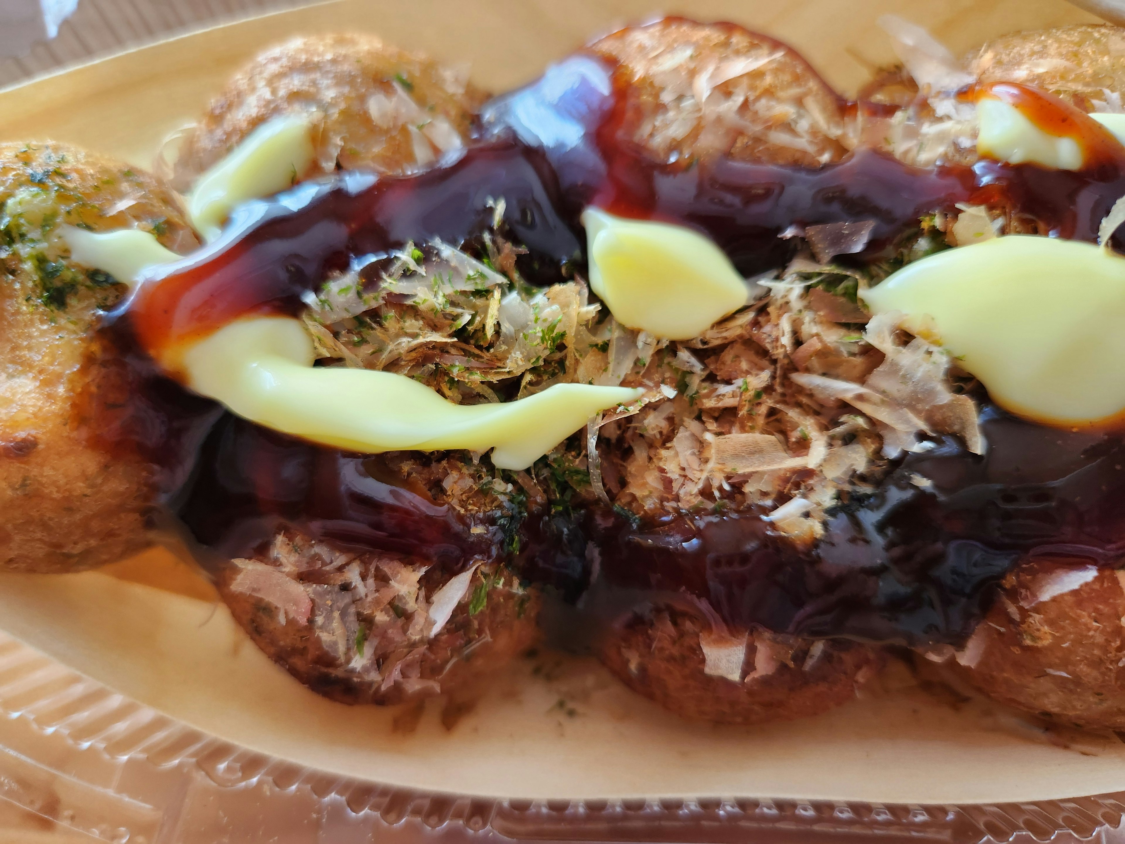 Piatto di takoyaki guarnito con salsa maionese scaglie di bonito e aonori