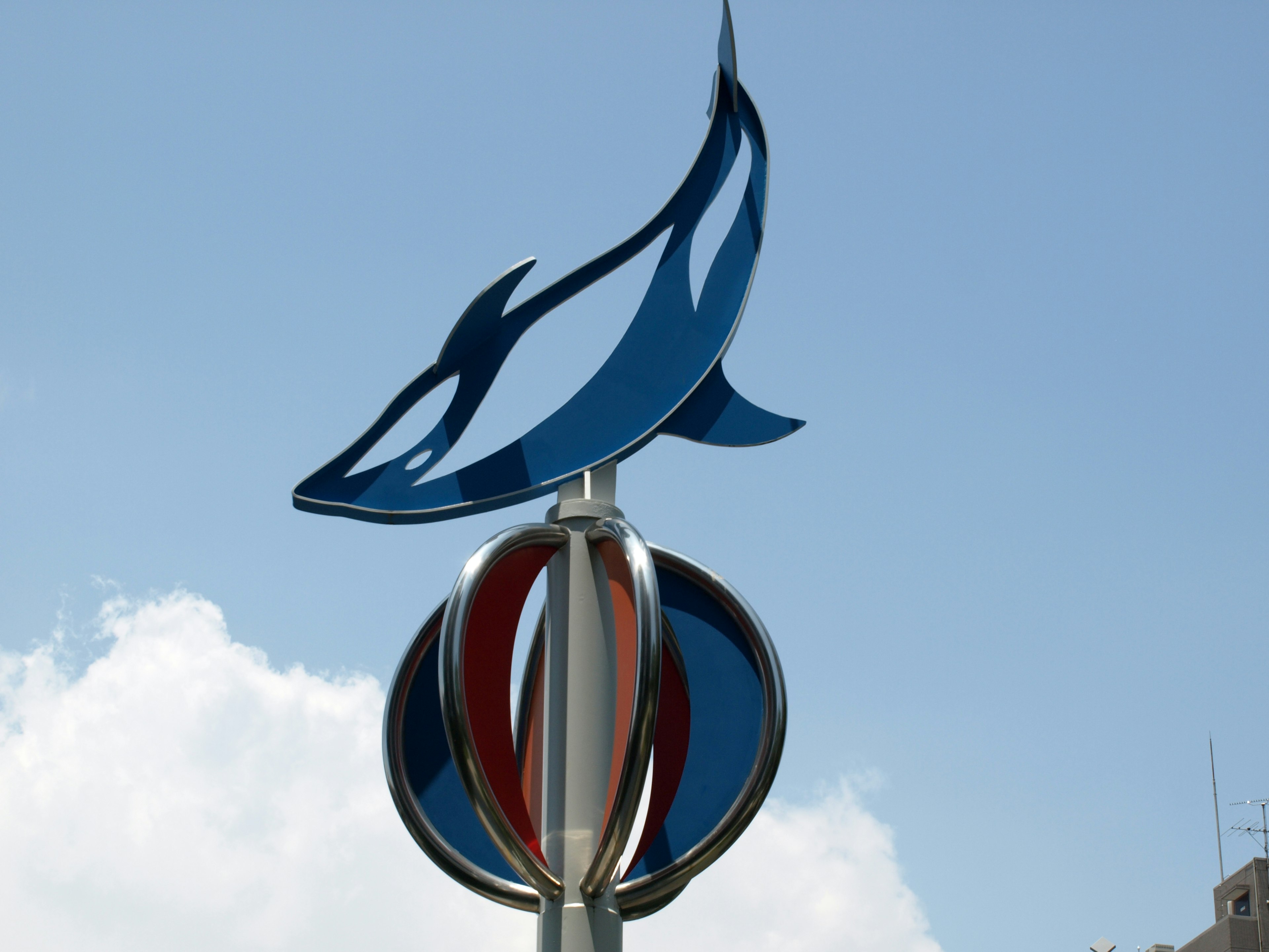 Stylized blue fish silhouette atop a colorful circular monument