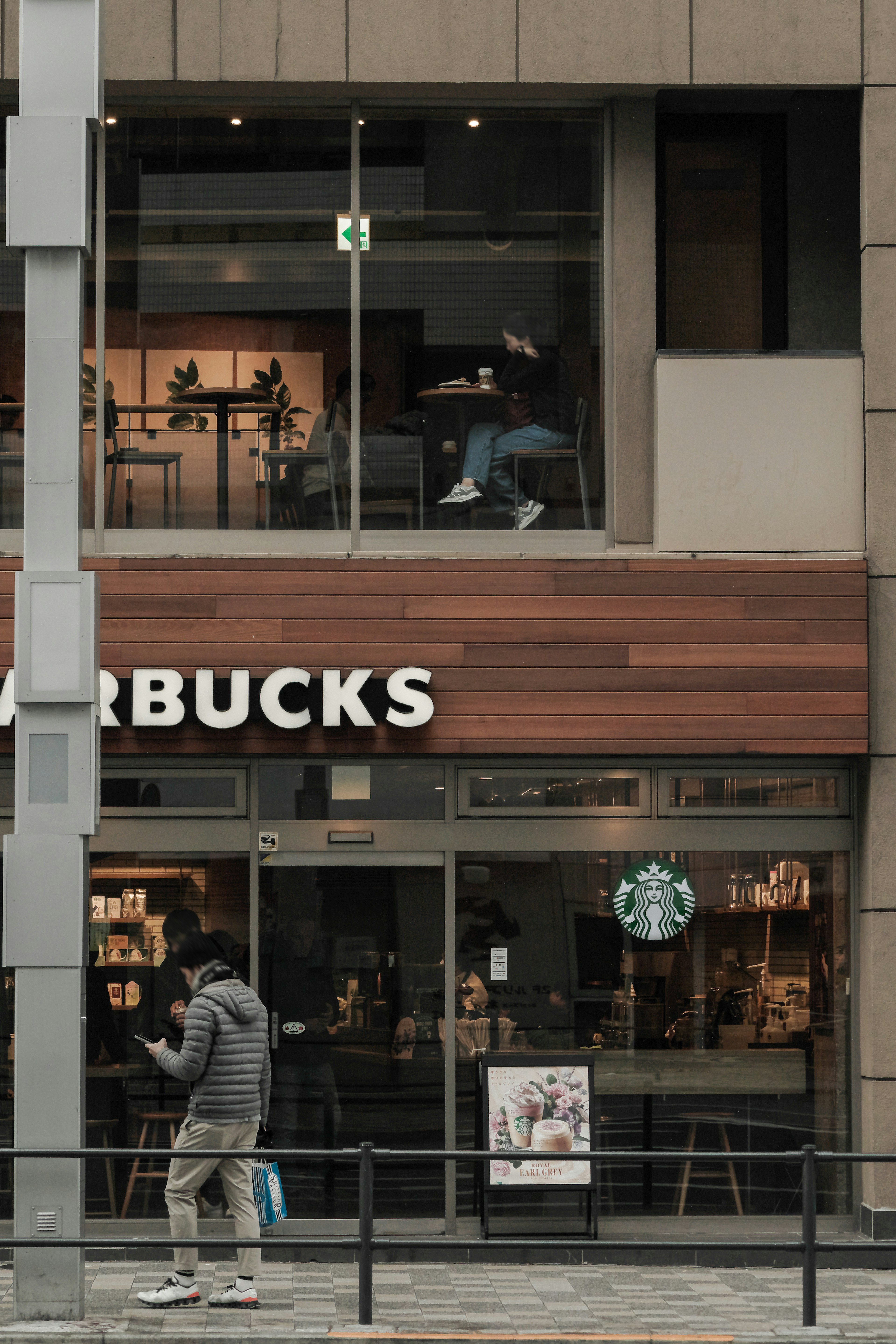 Exterior de Starbucks con una persona sentada junto a la ventana