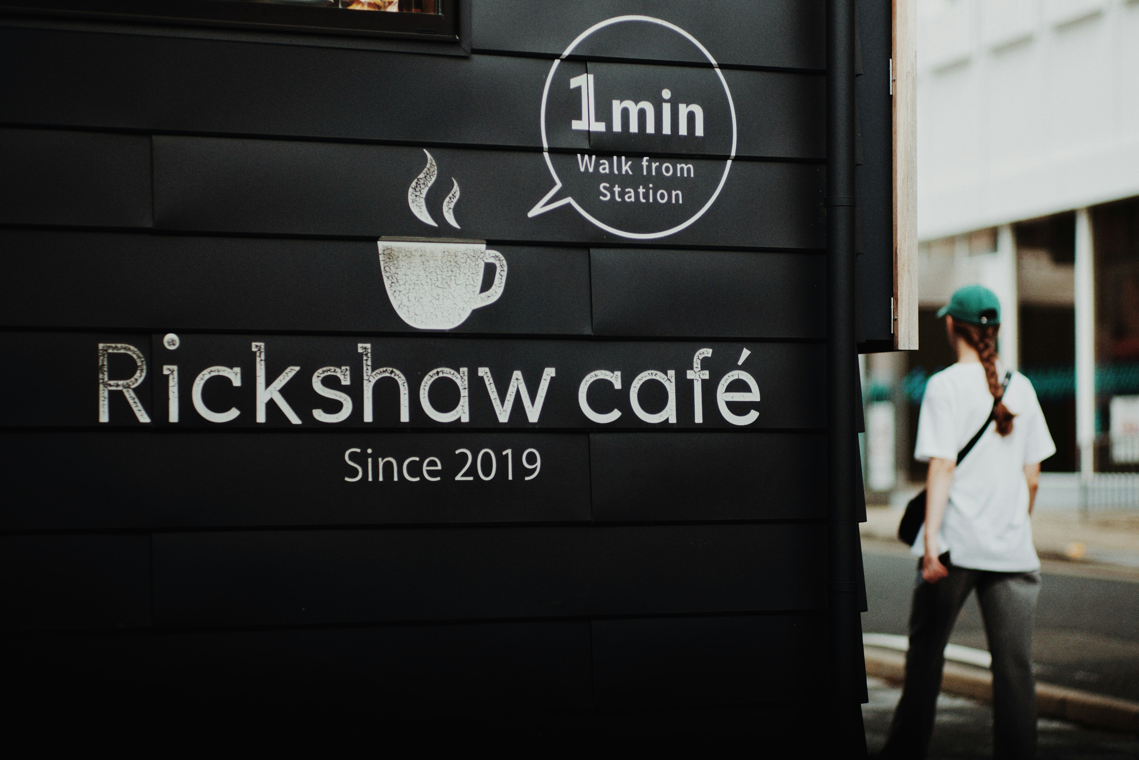 Sign of Rickshaw café showing establishment since 2019 and 1 minute walk from station