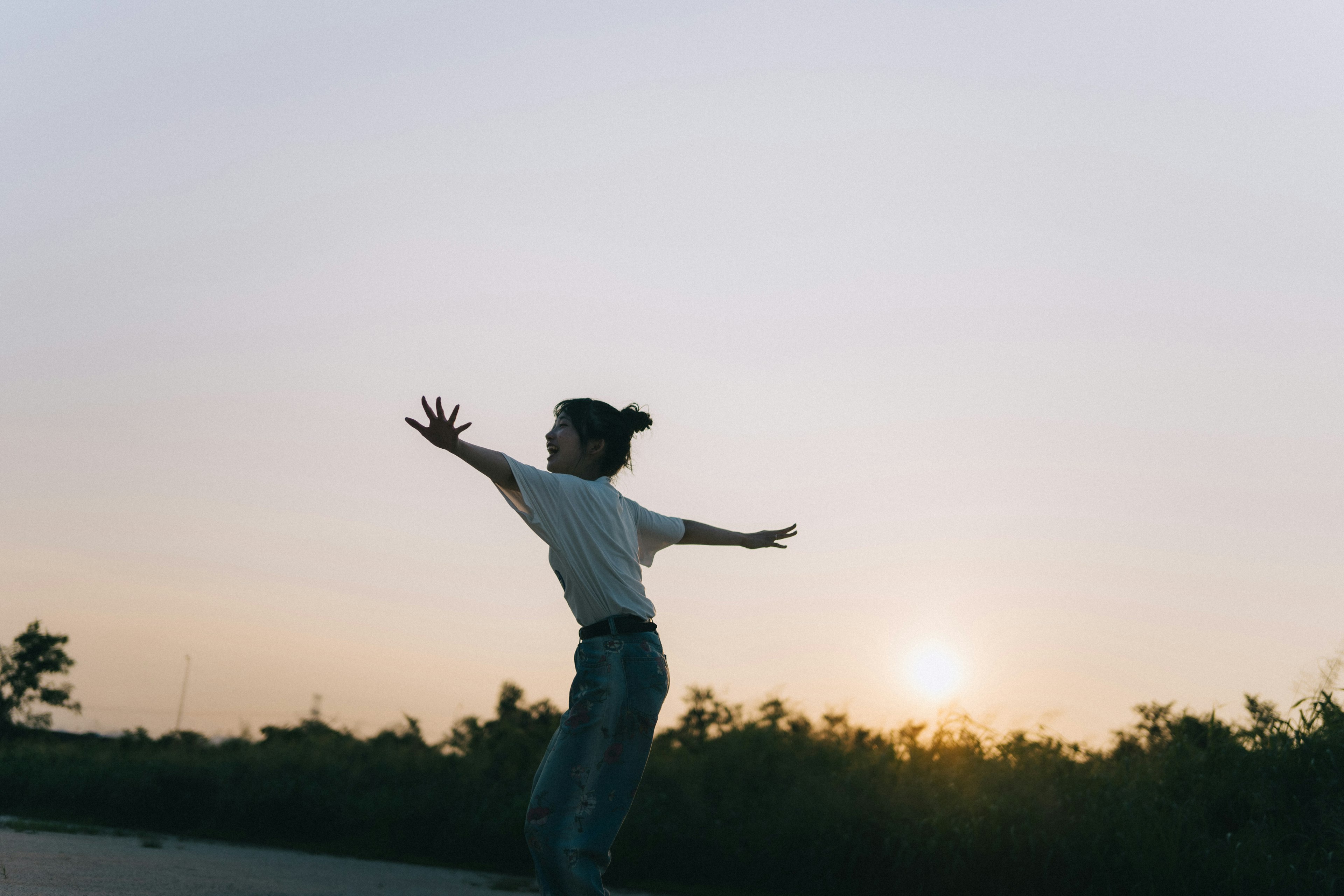 Silhouette di una donna che apre le braccia al tramonto