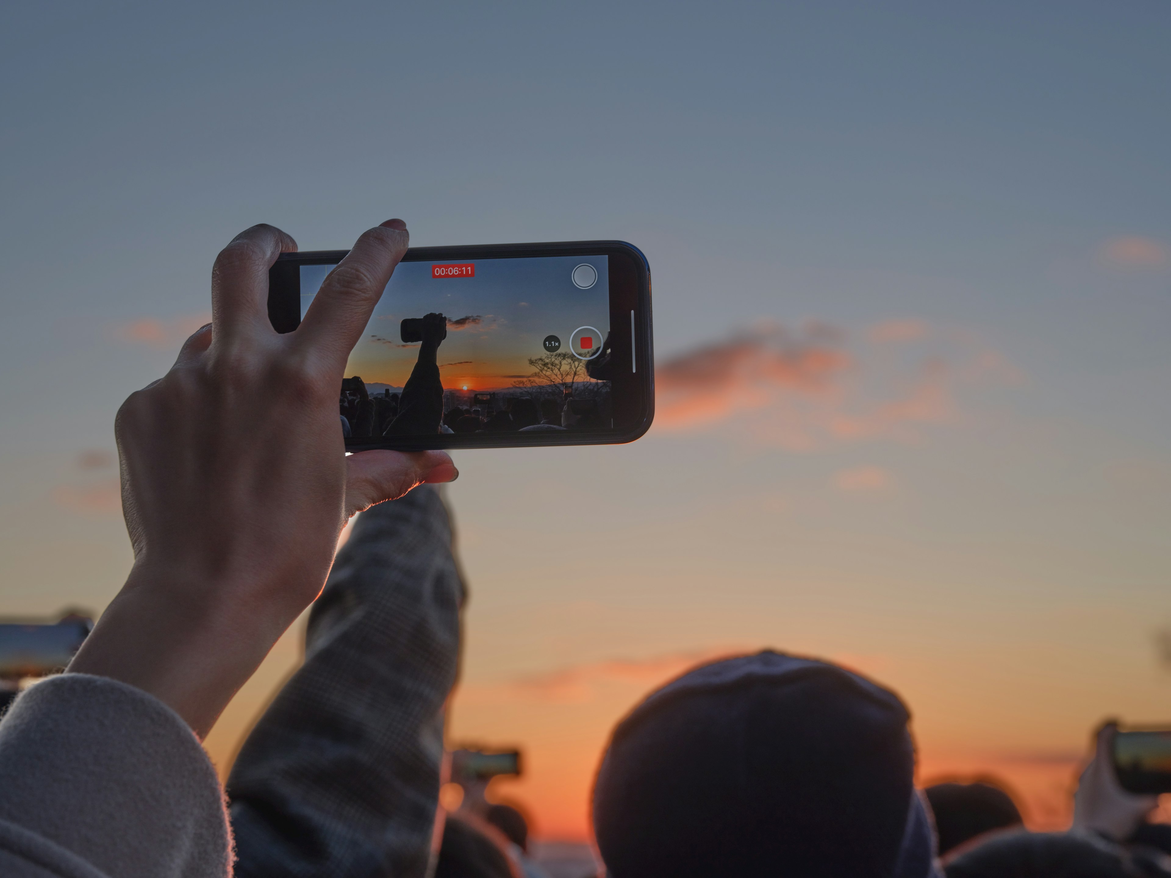 Menschen, die Smartphones halten und einen Sonnenuntergang aufnehmen