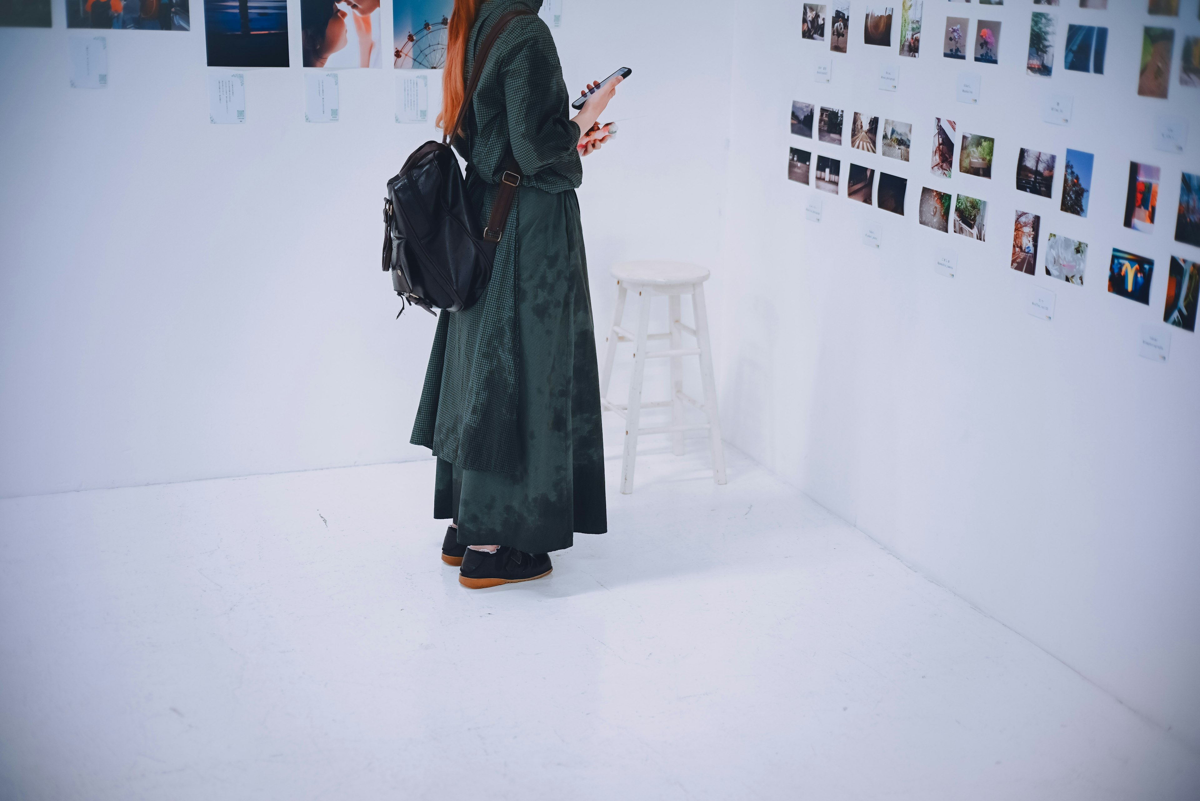 Una mujer con un abrigo verde observando una pared de fotografías