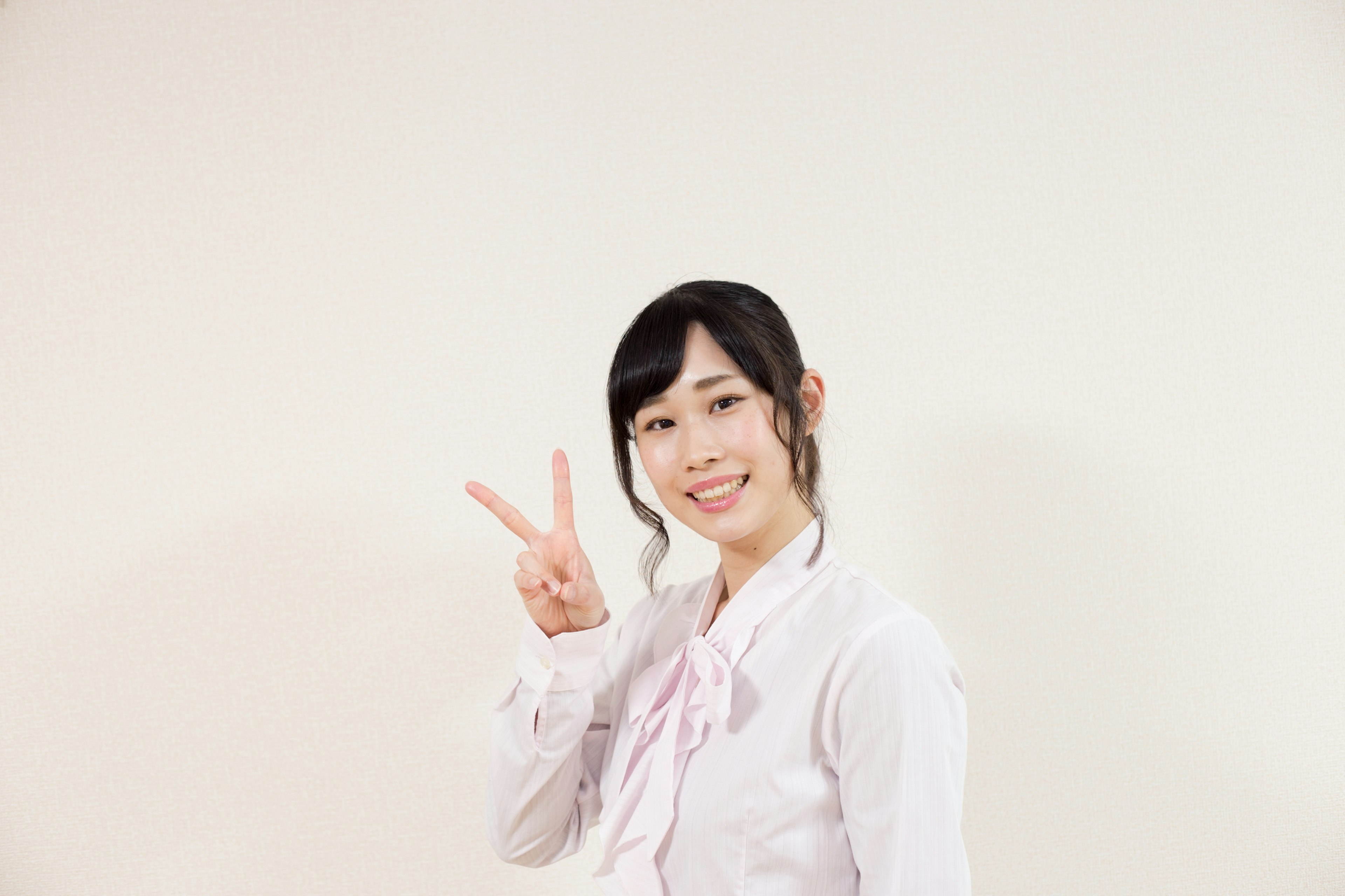 A woman wearing a white shirt making a peace sign