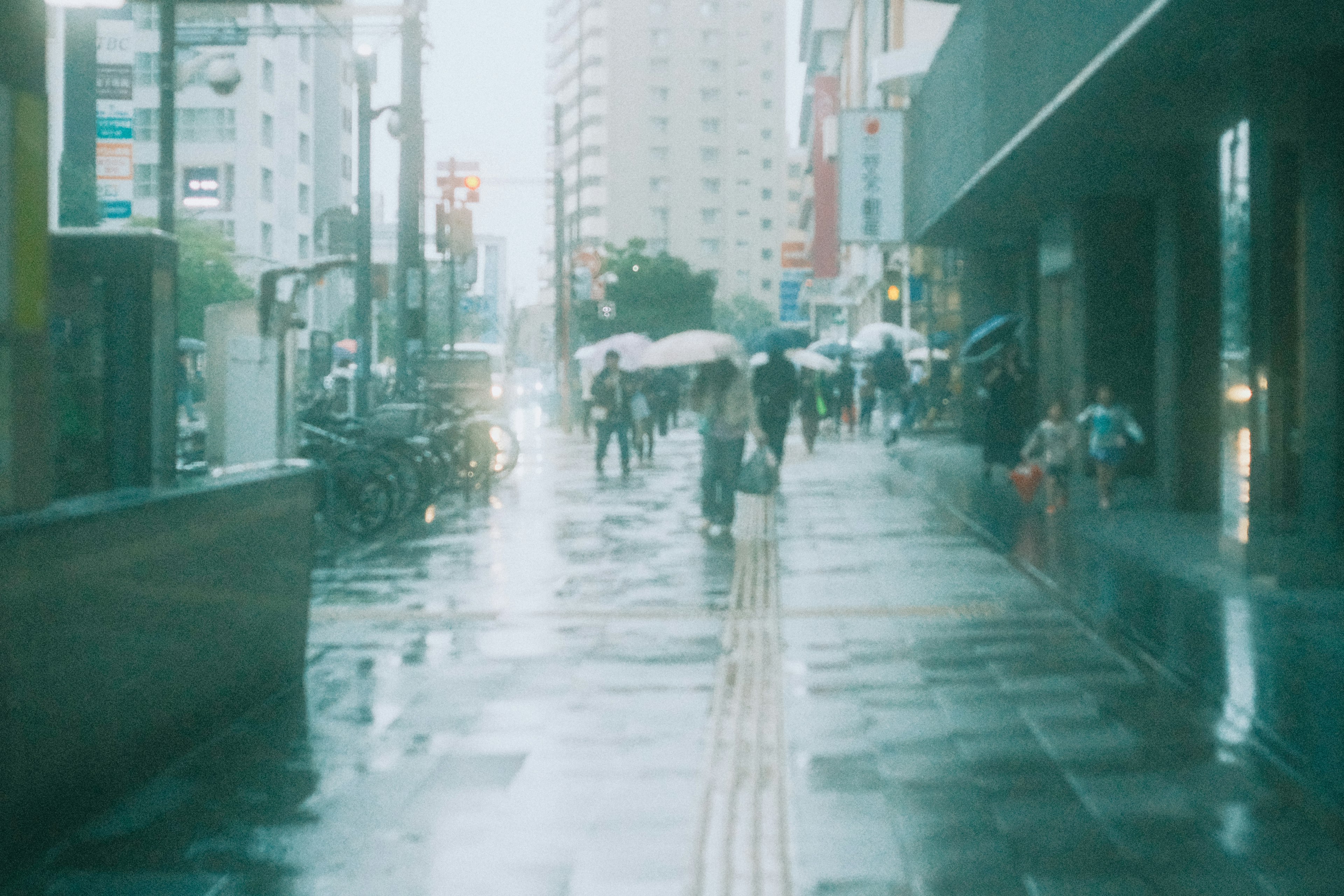 Escena urbana bajo la lluvia con personas caminando bajo paraguas