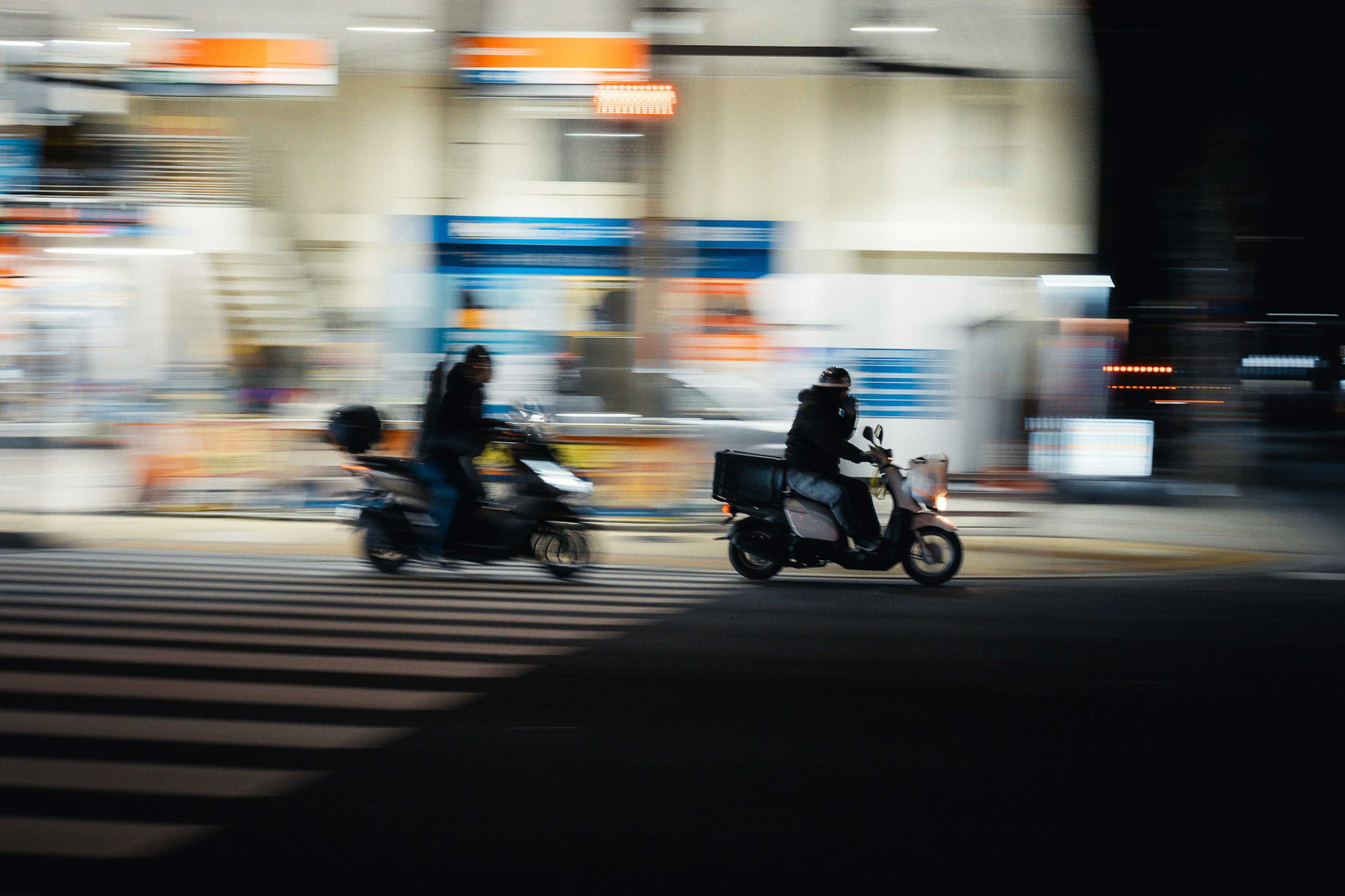 Zwei Motorräder überqueren eine Kreuzung in einer Stadt bei Nacht