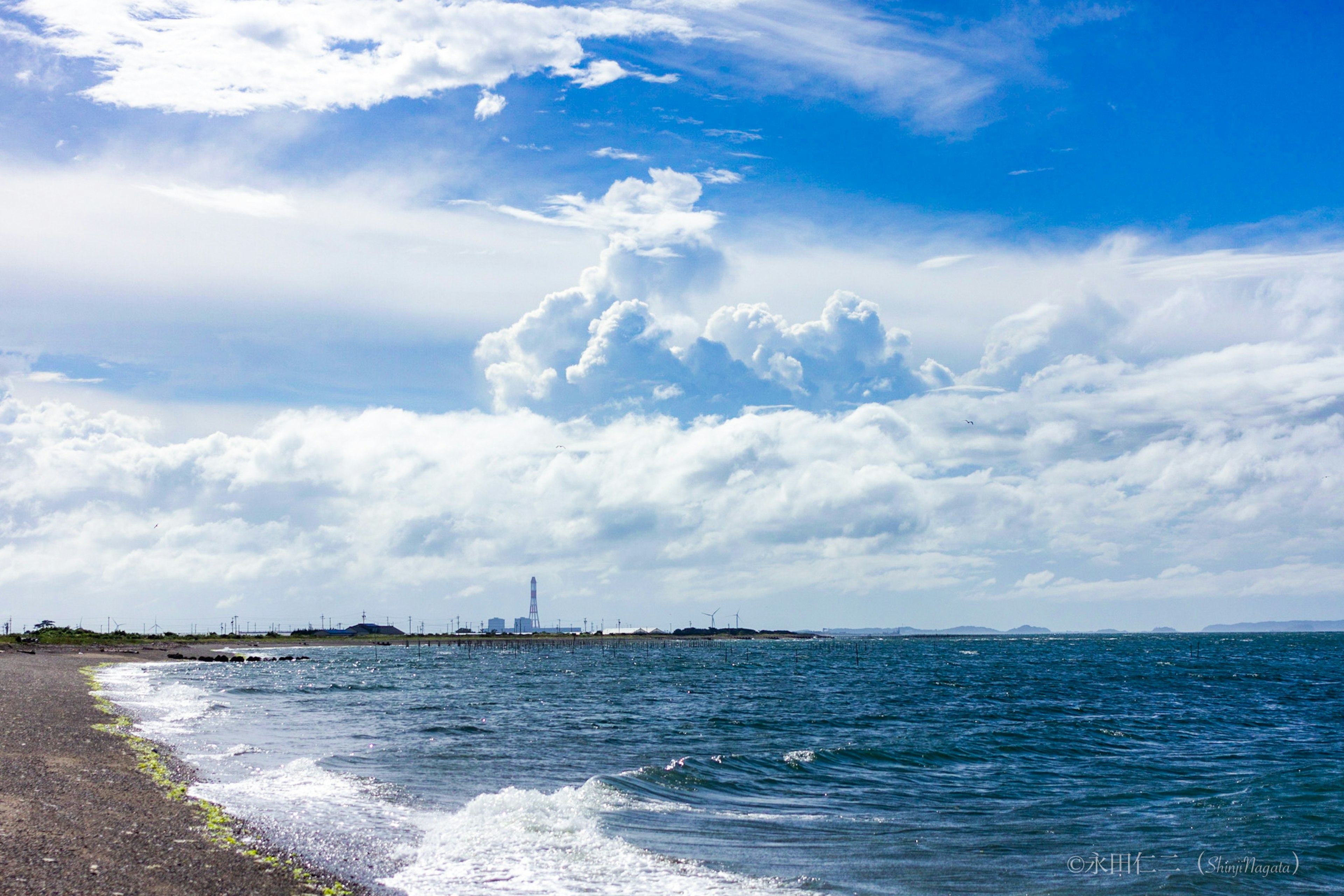 Coastal landscape featuring blue sky and fluffy white clouds