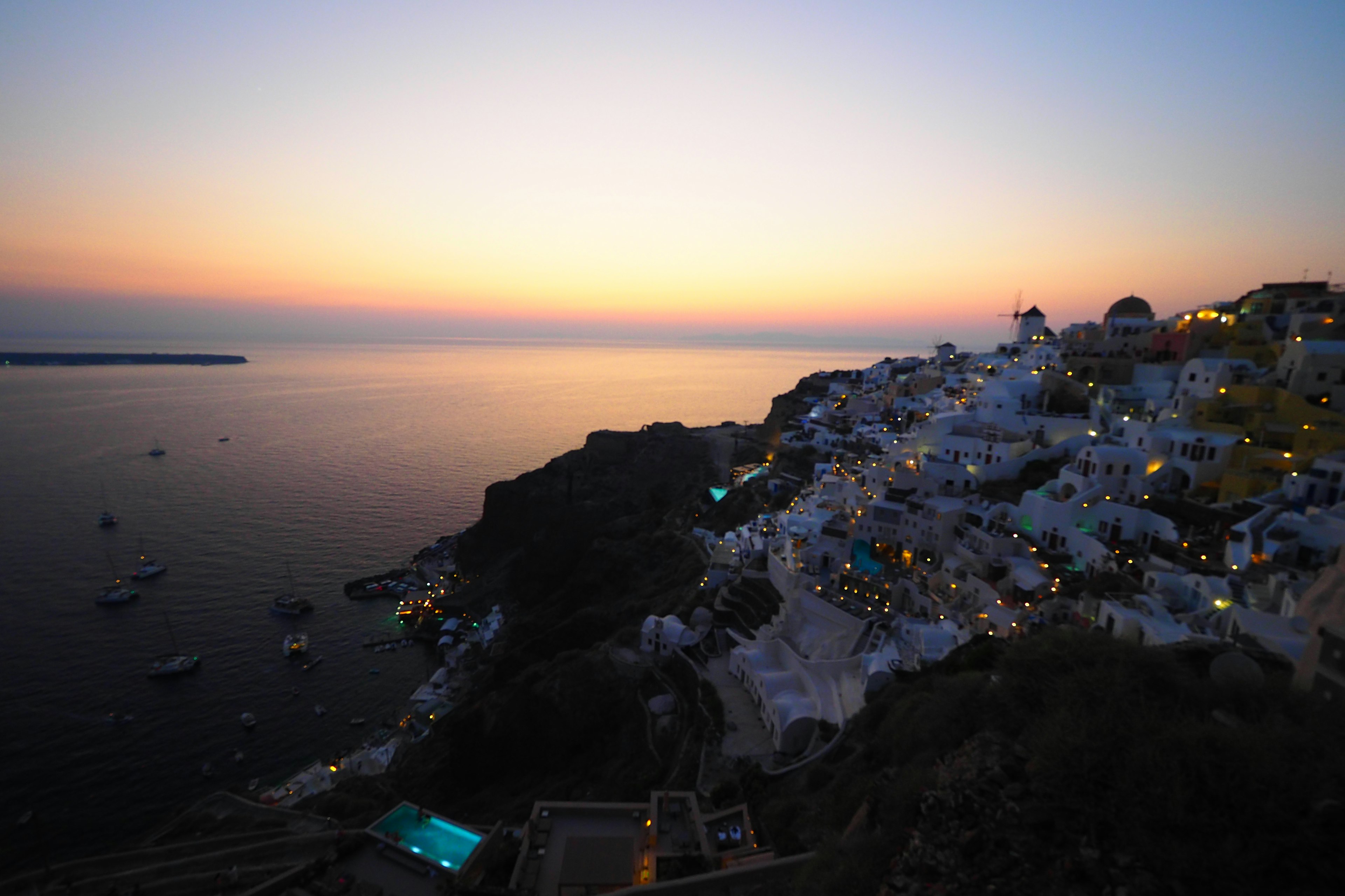 Vista del atardecer de Santorini con edificios blancos a lo largo de la costa