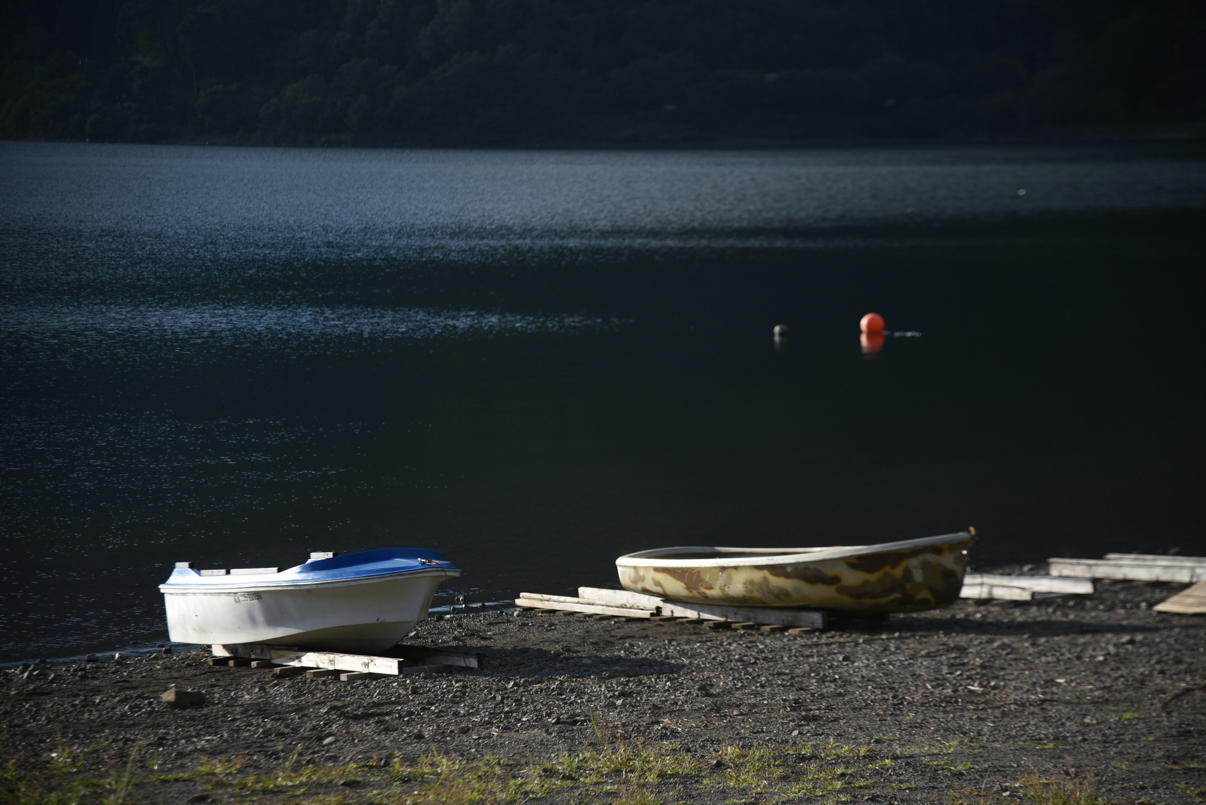 Two boats resting by the shore of a tranquil lake