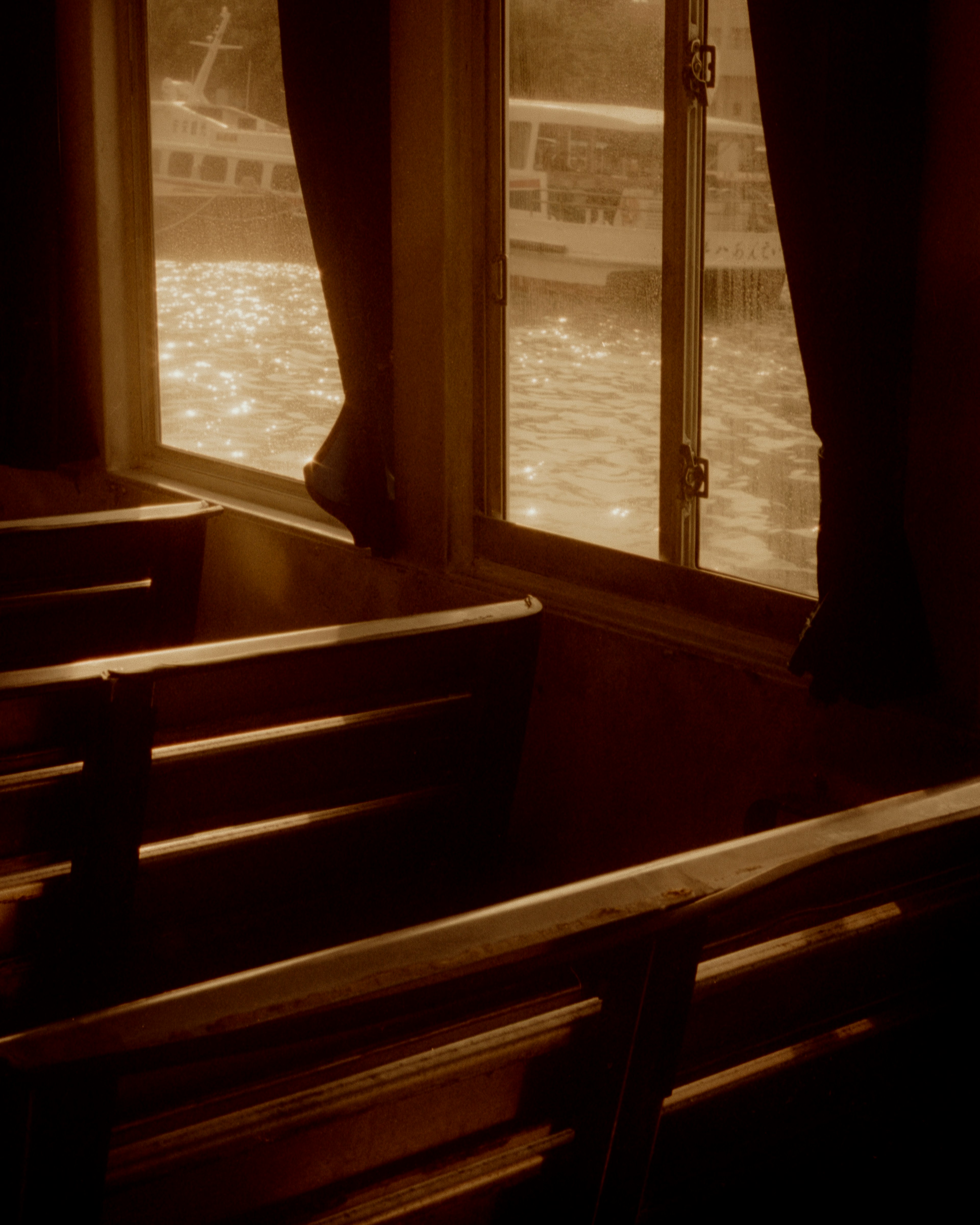 Wooden benches with curtains and a view of the water through the window