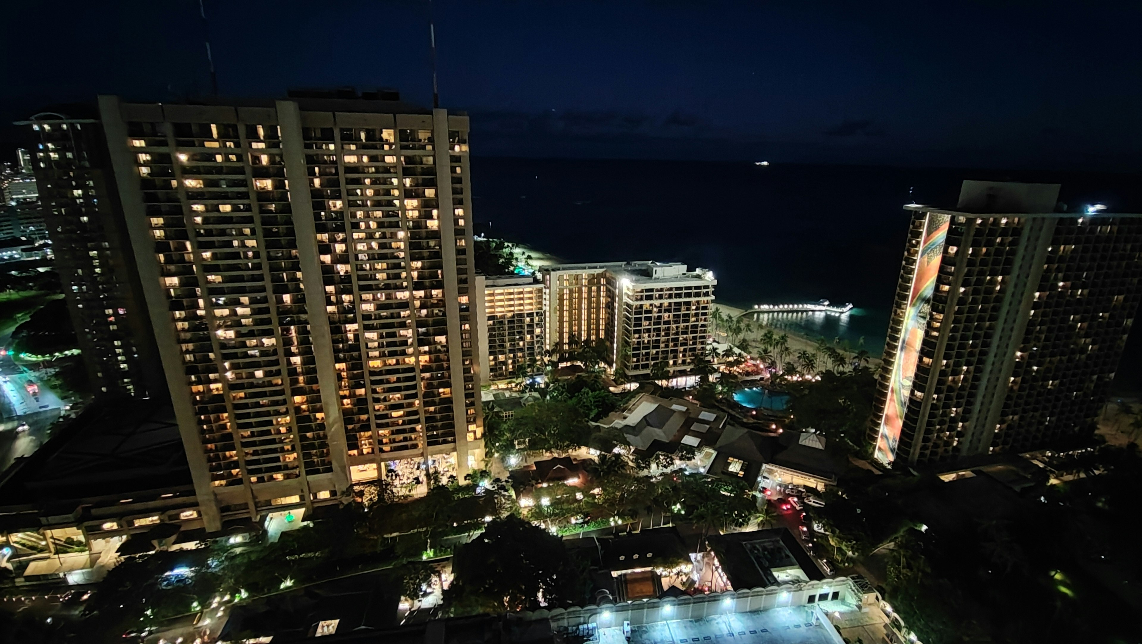 Nachtansicht der Skyline von Honolulu mit beleuchteten Gebäuden und Ozean