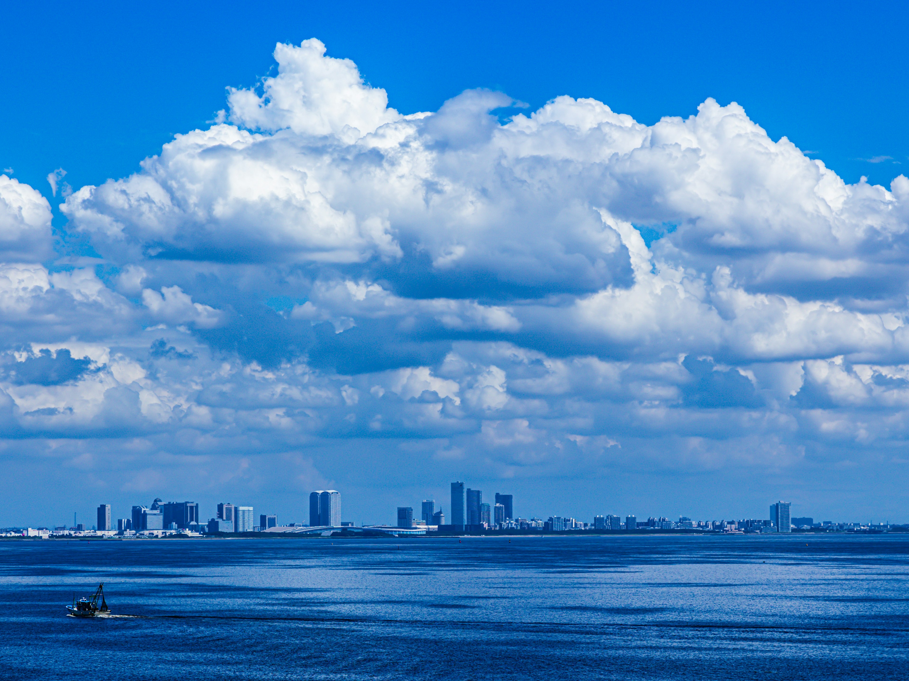 Stadtansicht unter einem blauen Himmel mit flauschigen Wolken über ruhigem Wasser