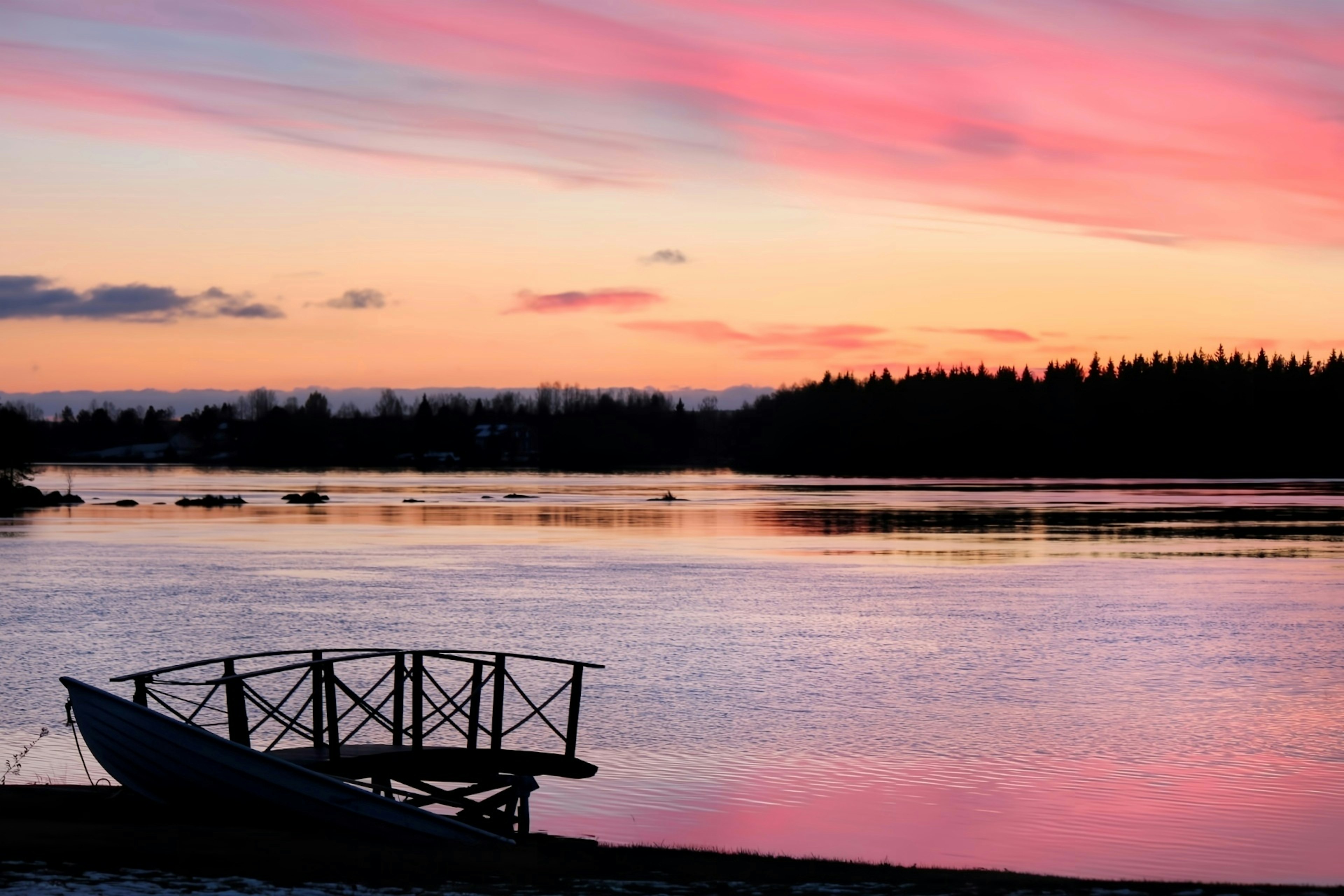 Vue pittoresque d'un ciel au coucher du soleil avec des couleurs vives et une surface d'eau calme avec un petit bateau sur le rivage