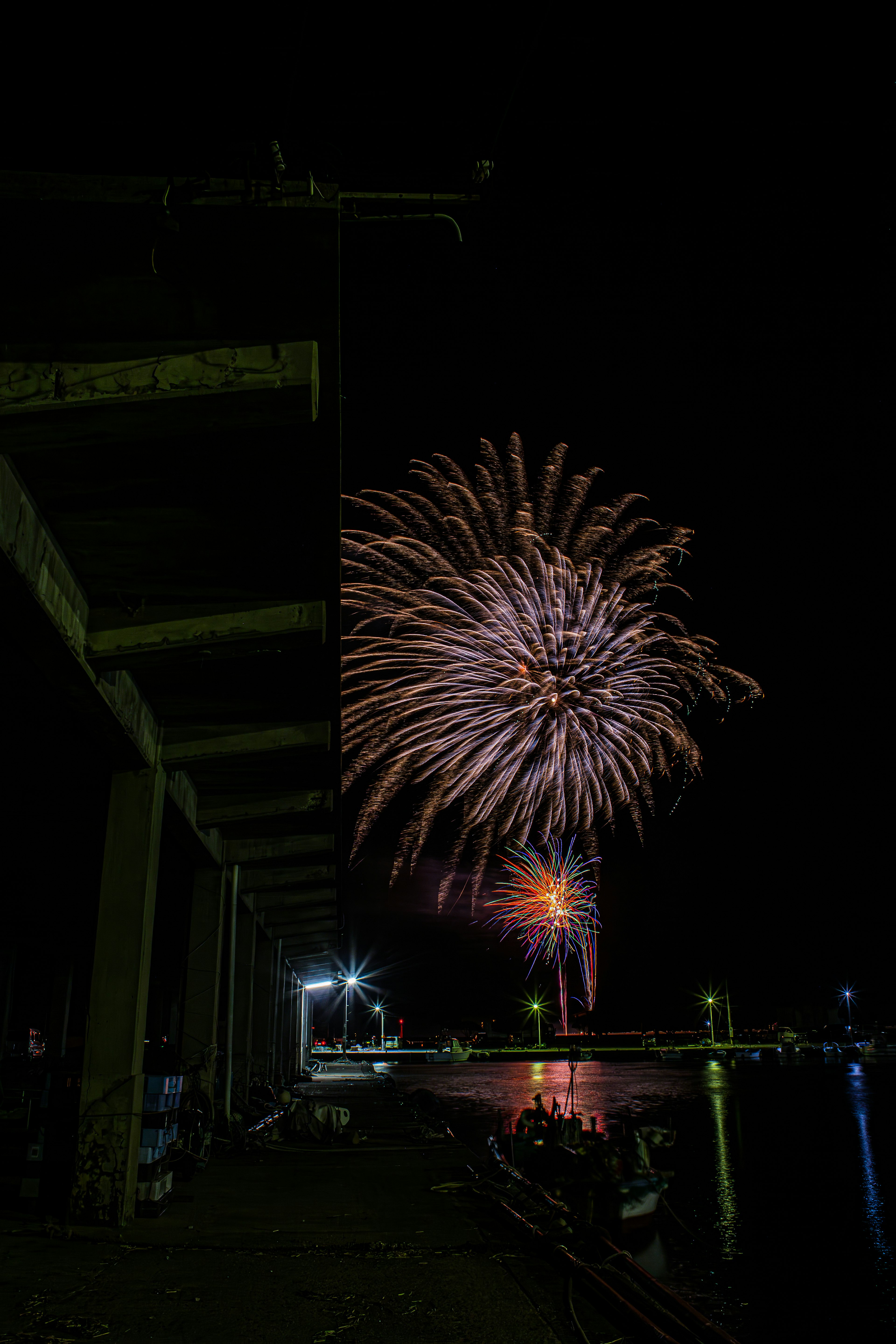 Colorful fireworks display over a pier at night