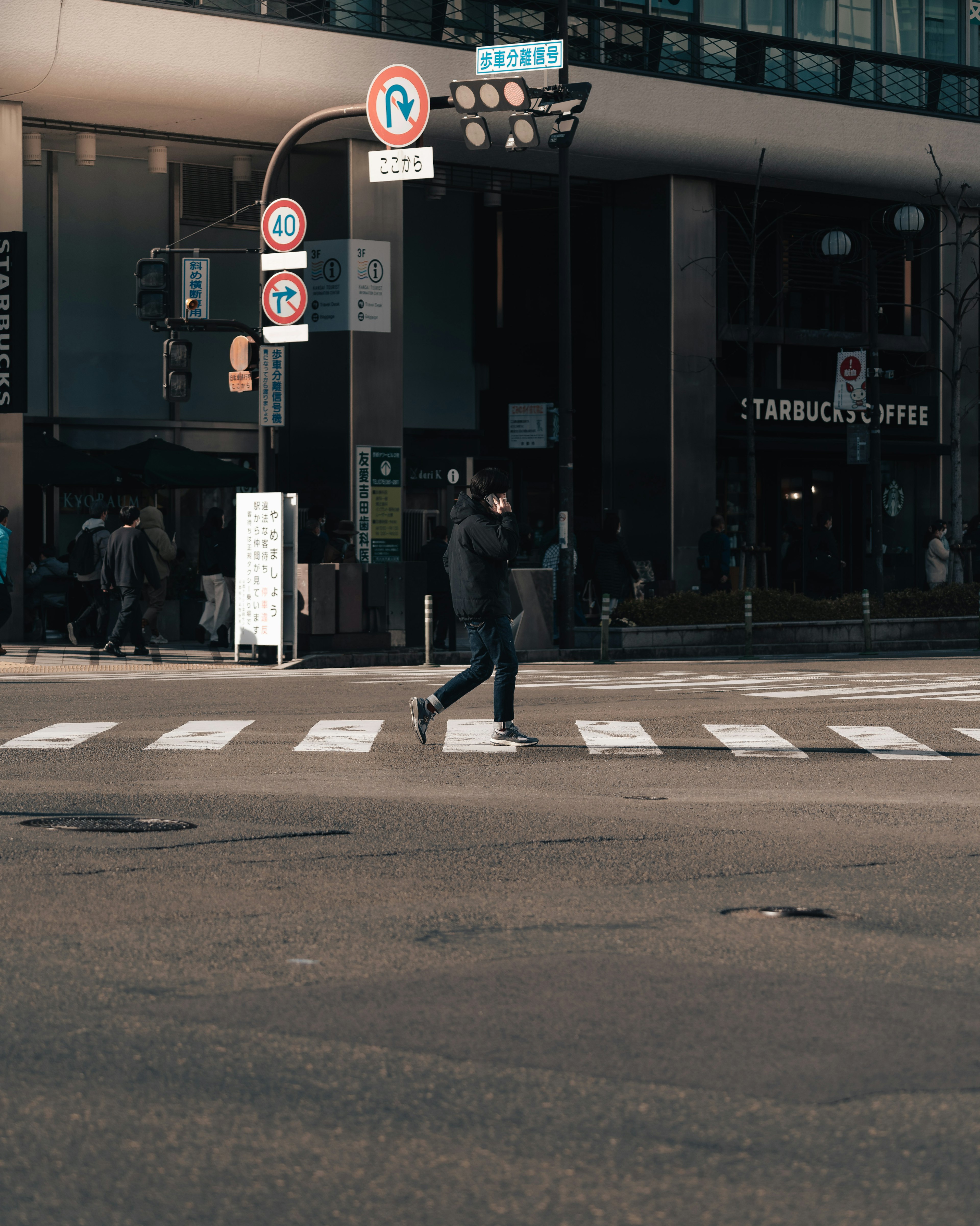 A person crossing a street at an intersection near a Starbucks