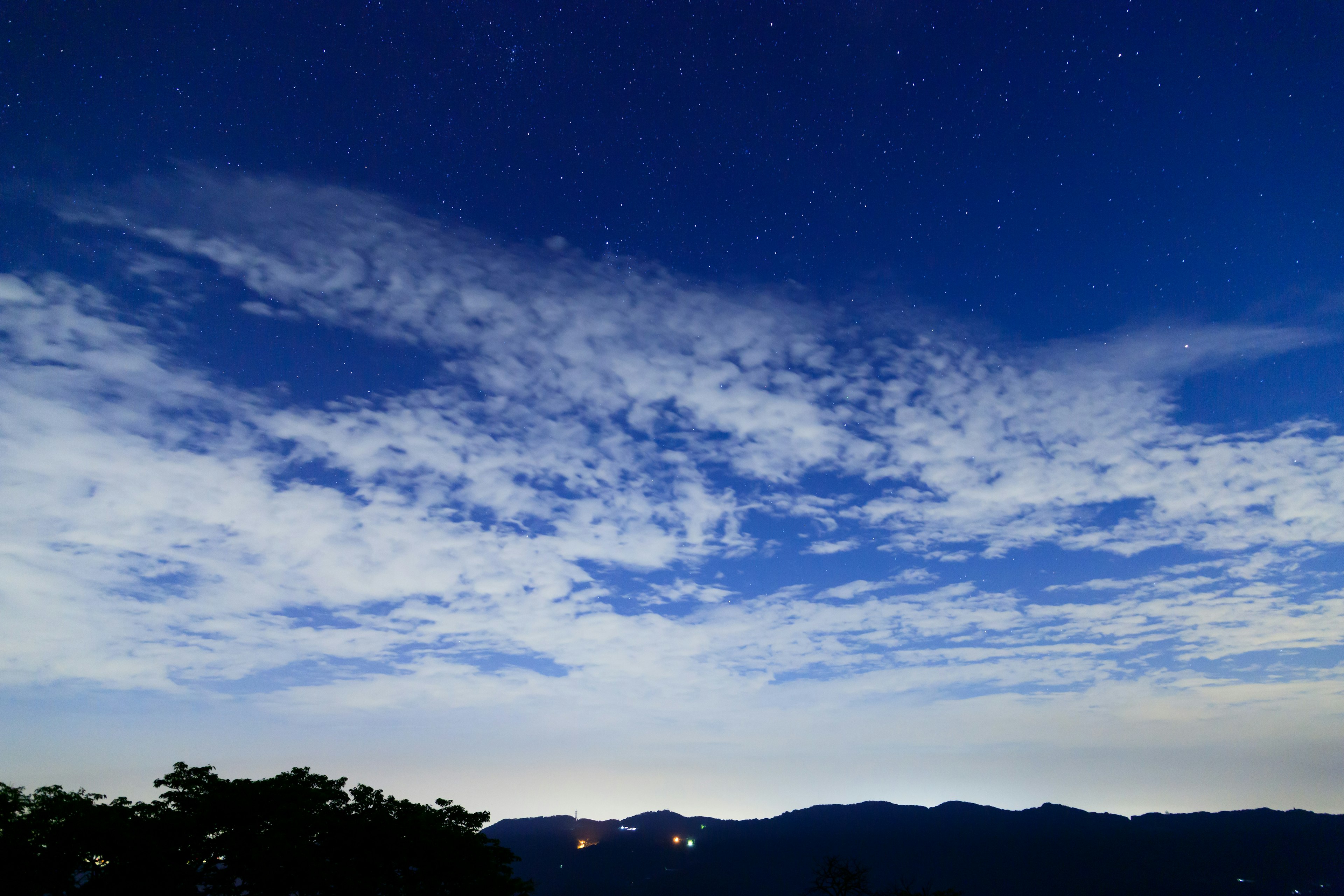 Foto eines blauen Himmels mit leuchtenden Sternen und verstreuten Wolken