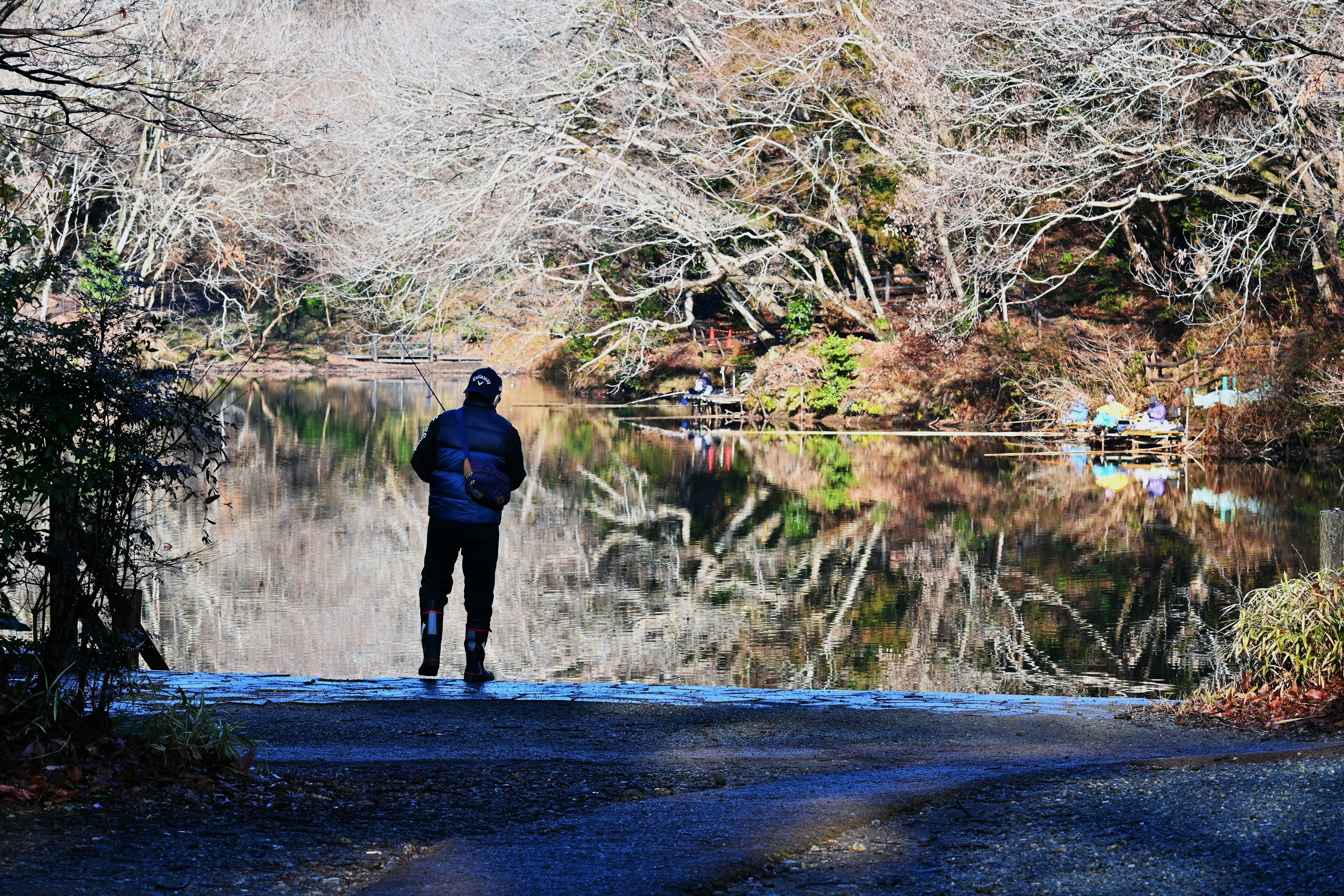 Une personne se tenant au bord d'un lac tranquille reflétant les environs