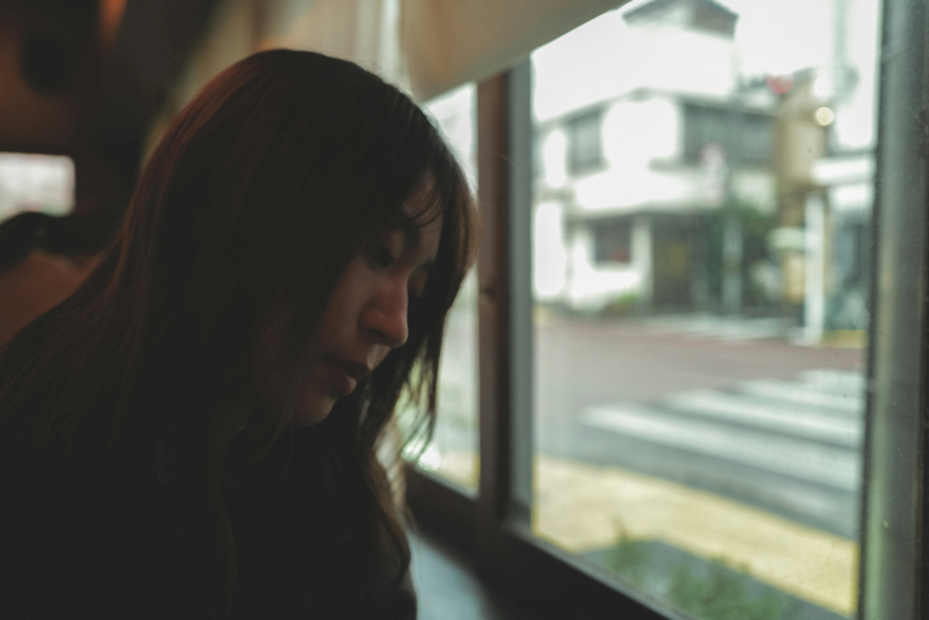 Profile of a woman sitting by a window with a view of the street