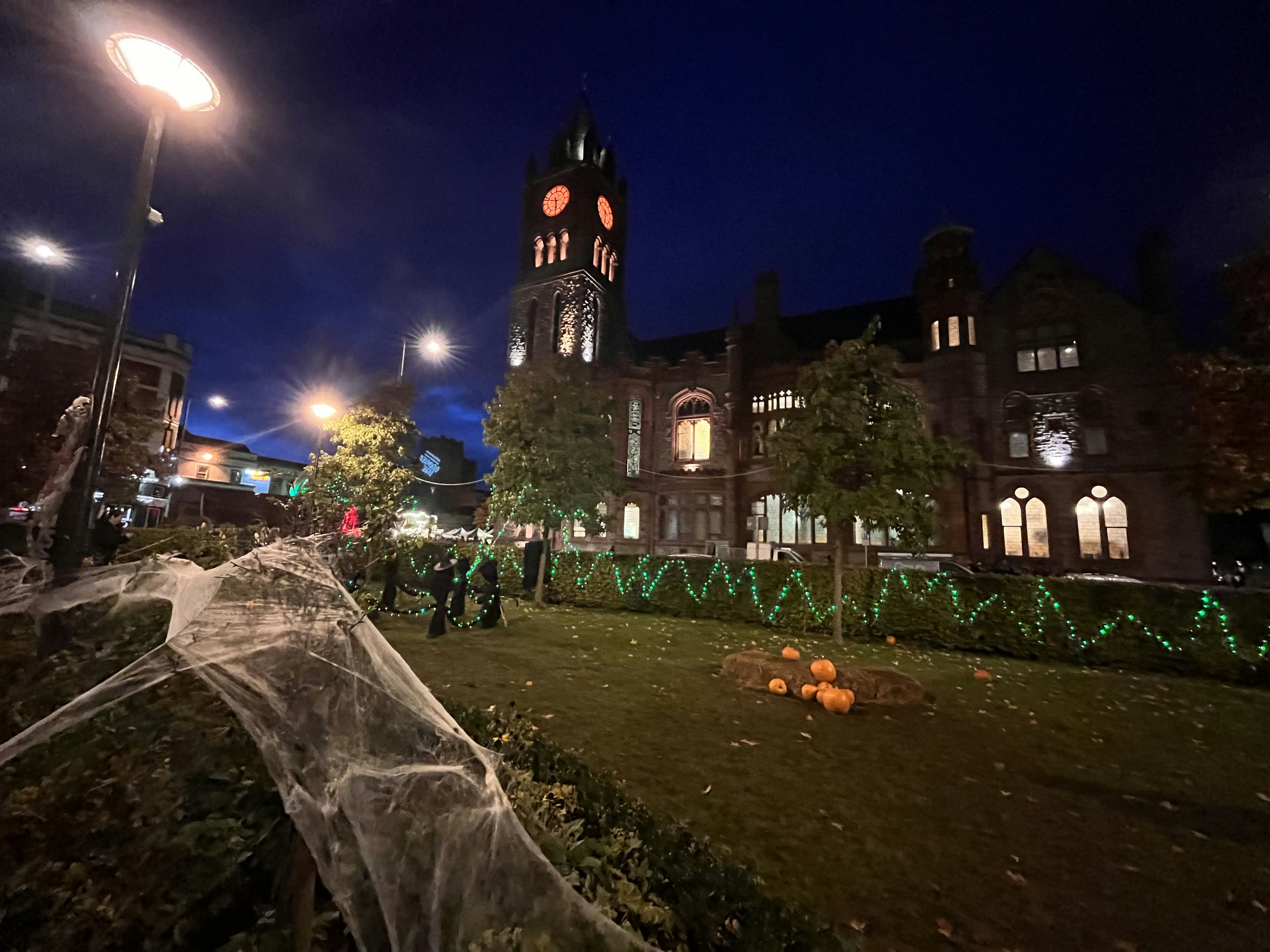 夜の街角に立つ歴史的な建物と時計塔 ハロウィンの装飾とクモの巣が目を引く