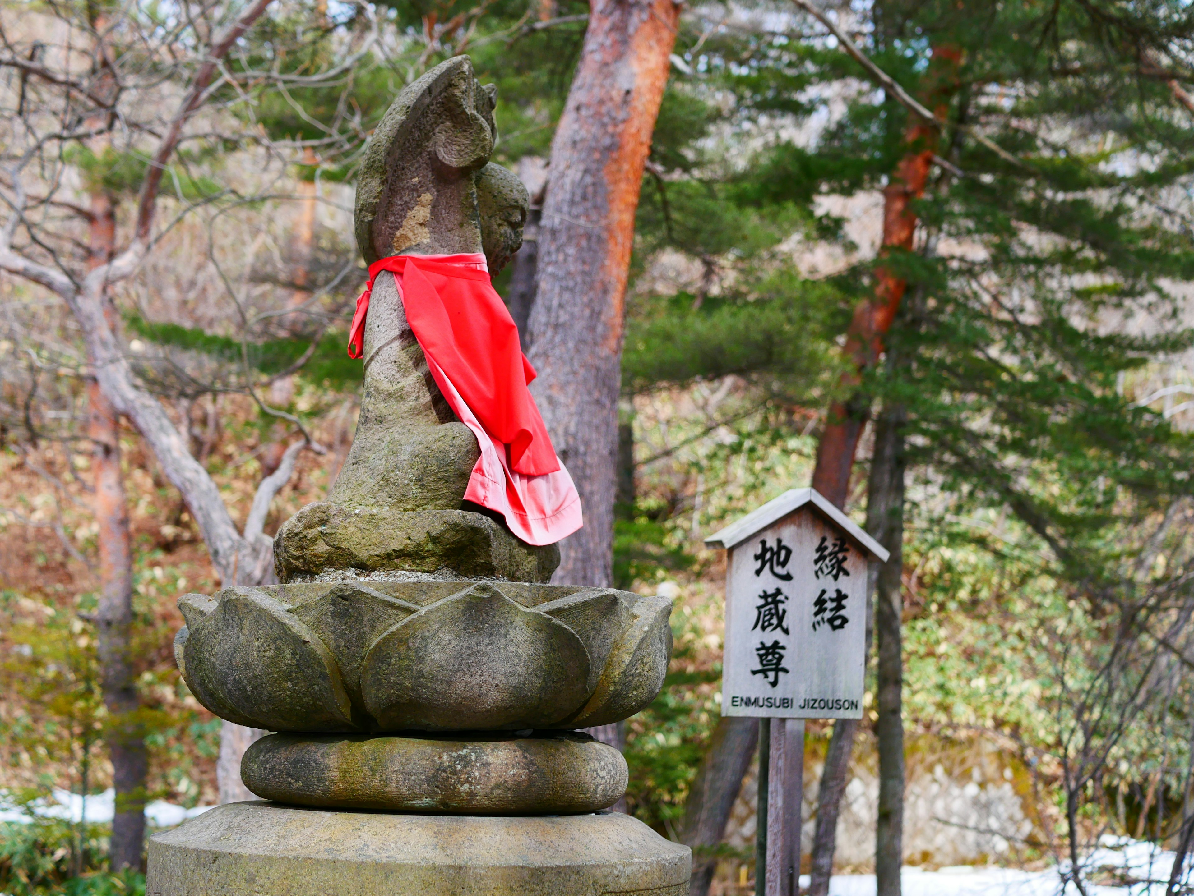 赤い布を着た石の像が蓮の花の上に立っている風景