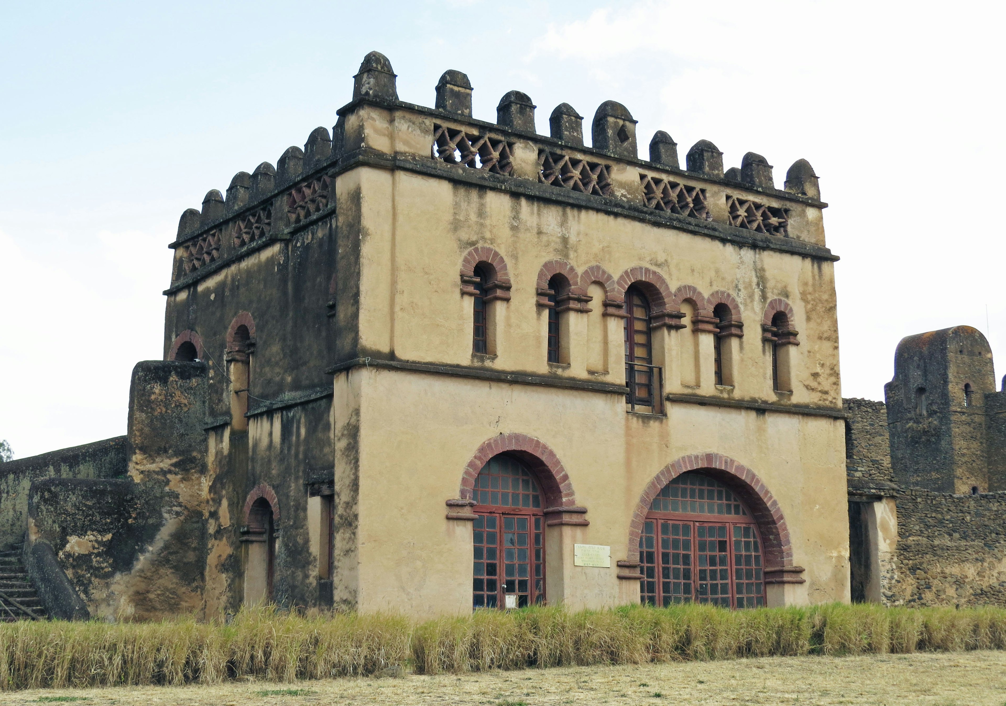 Exterior de un edificio histórico con ventanas rojas y elementos decorativos en el techo