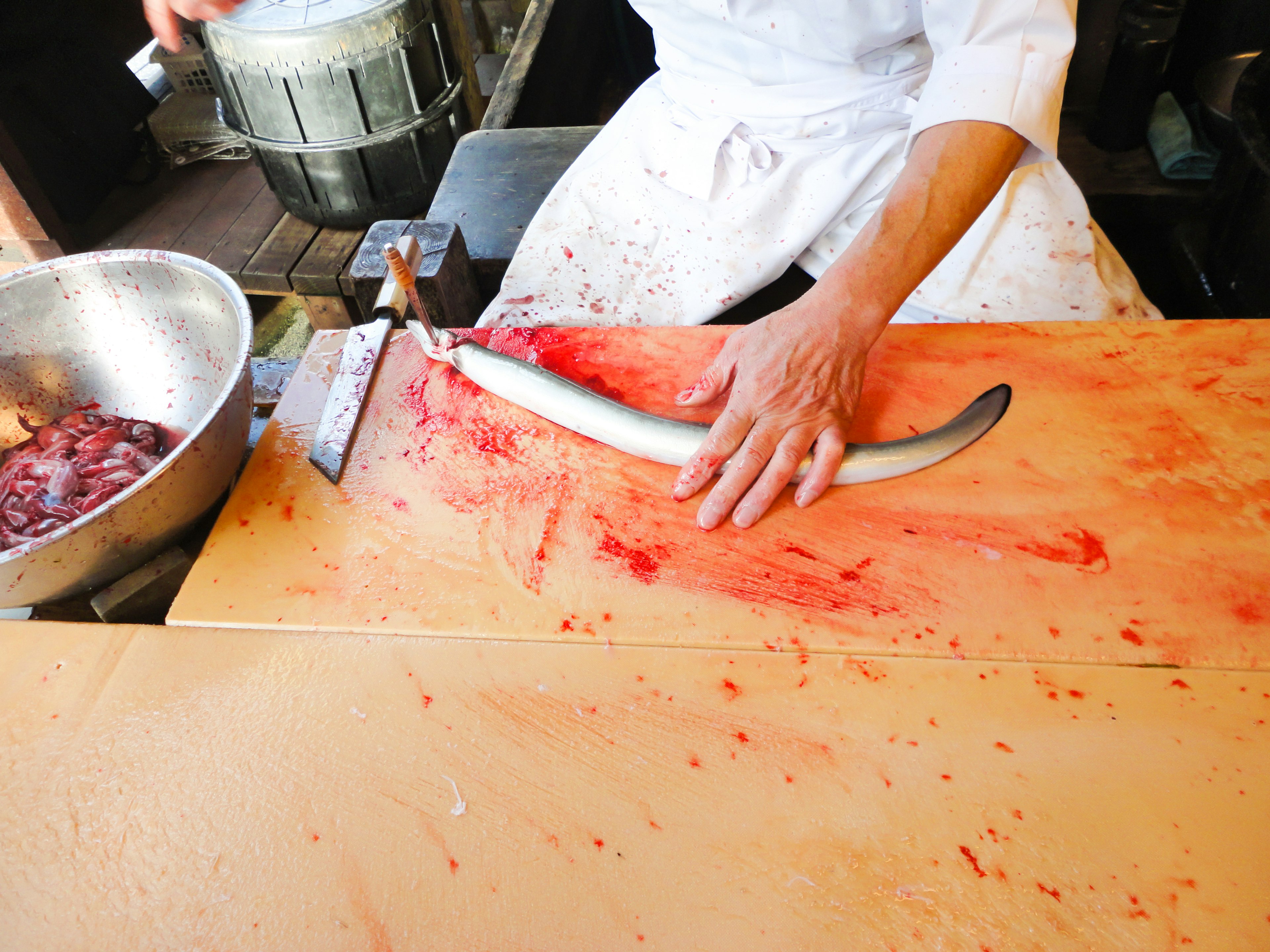 Chef filleting a fish on a bloody cutting board