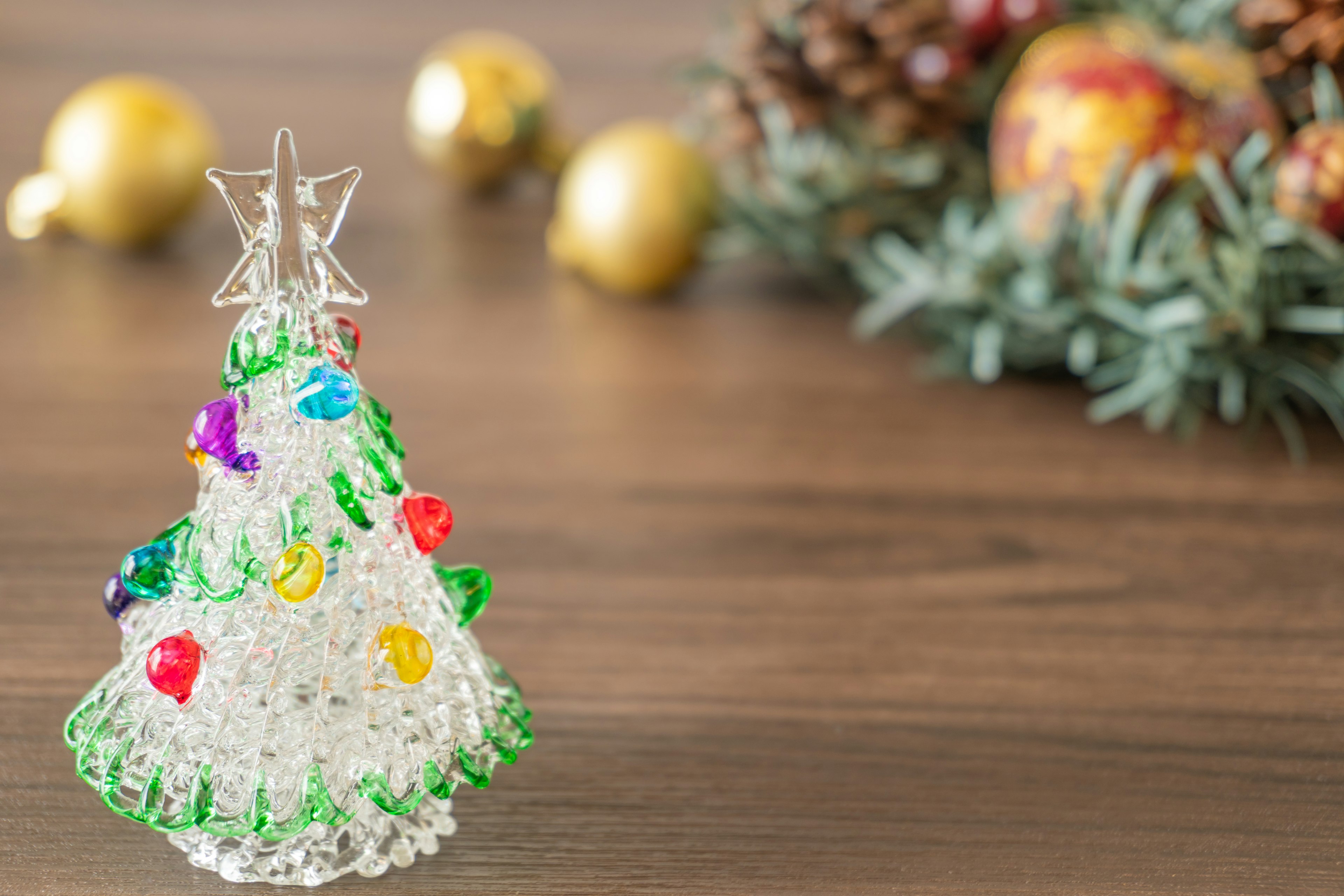 Árbol de Navidad decorativo de vidrio con cuentas coloridas sobre una superficie de madera