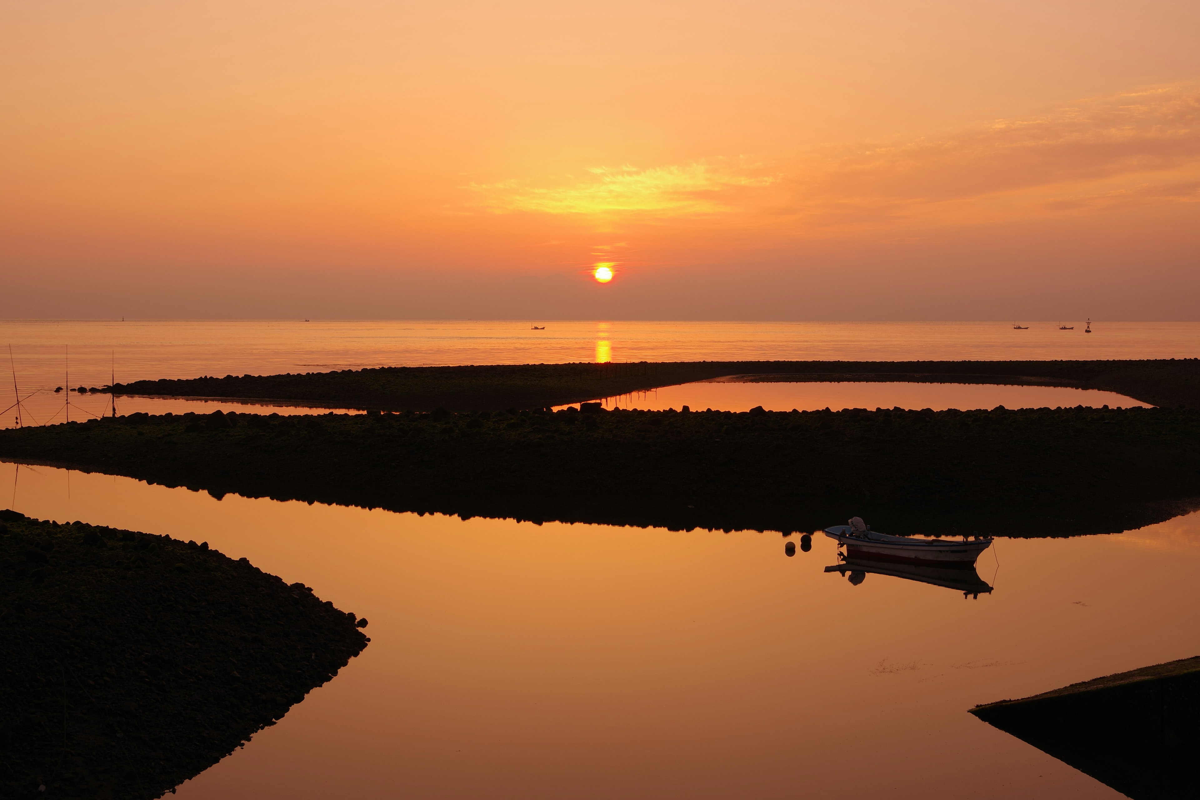 Sunset over calm waters with a small boat