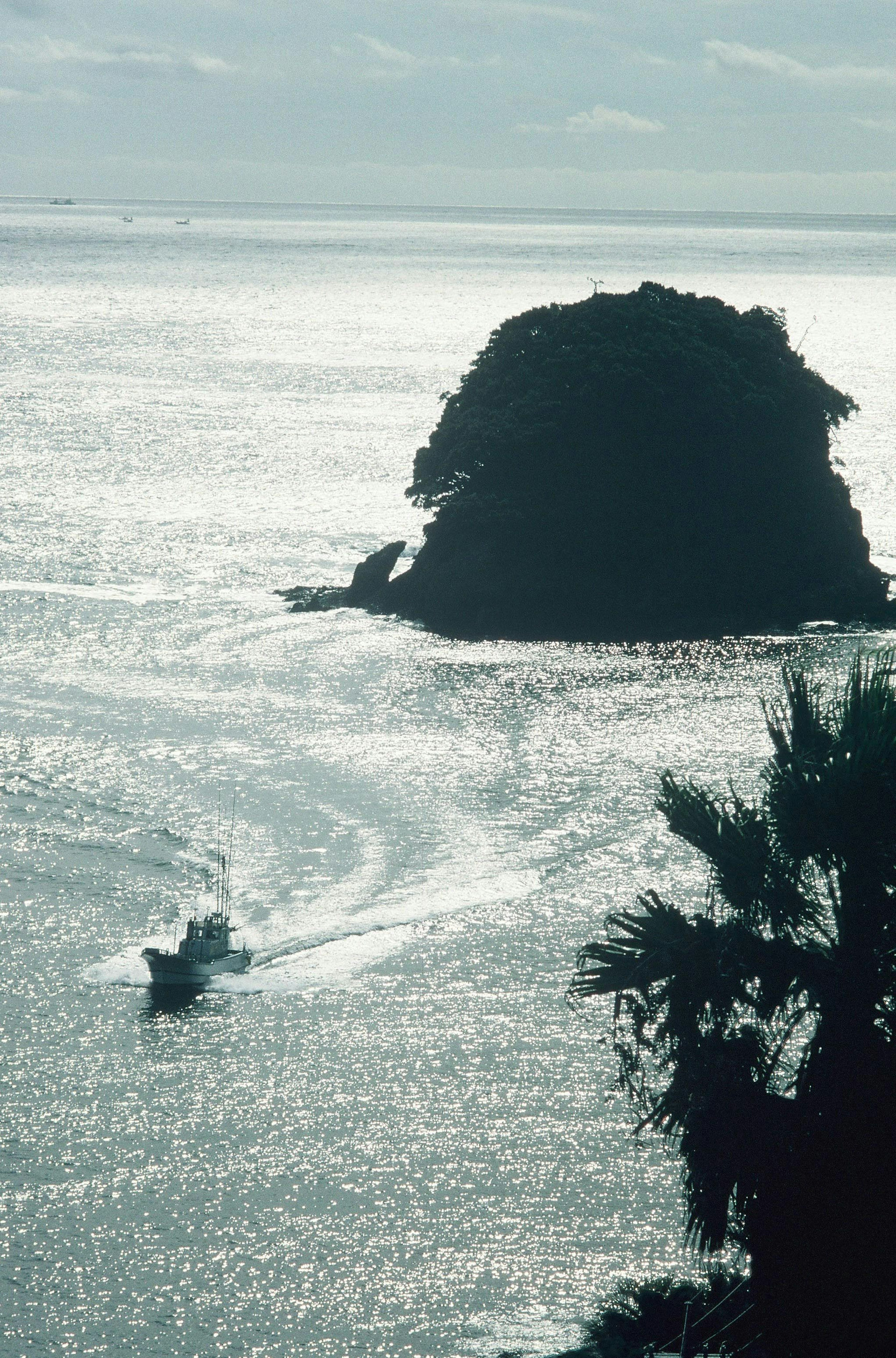 Vista de una roca en el mar con un bote navegando cerca