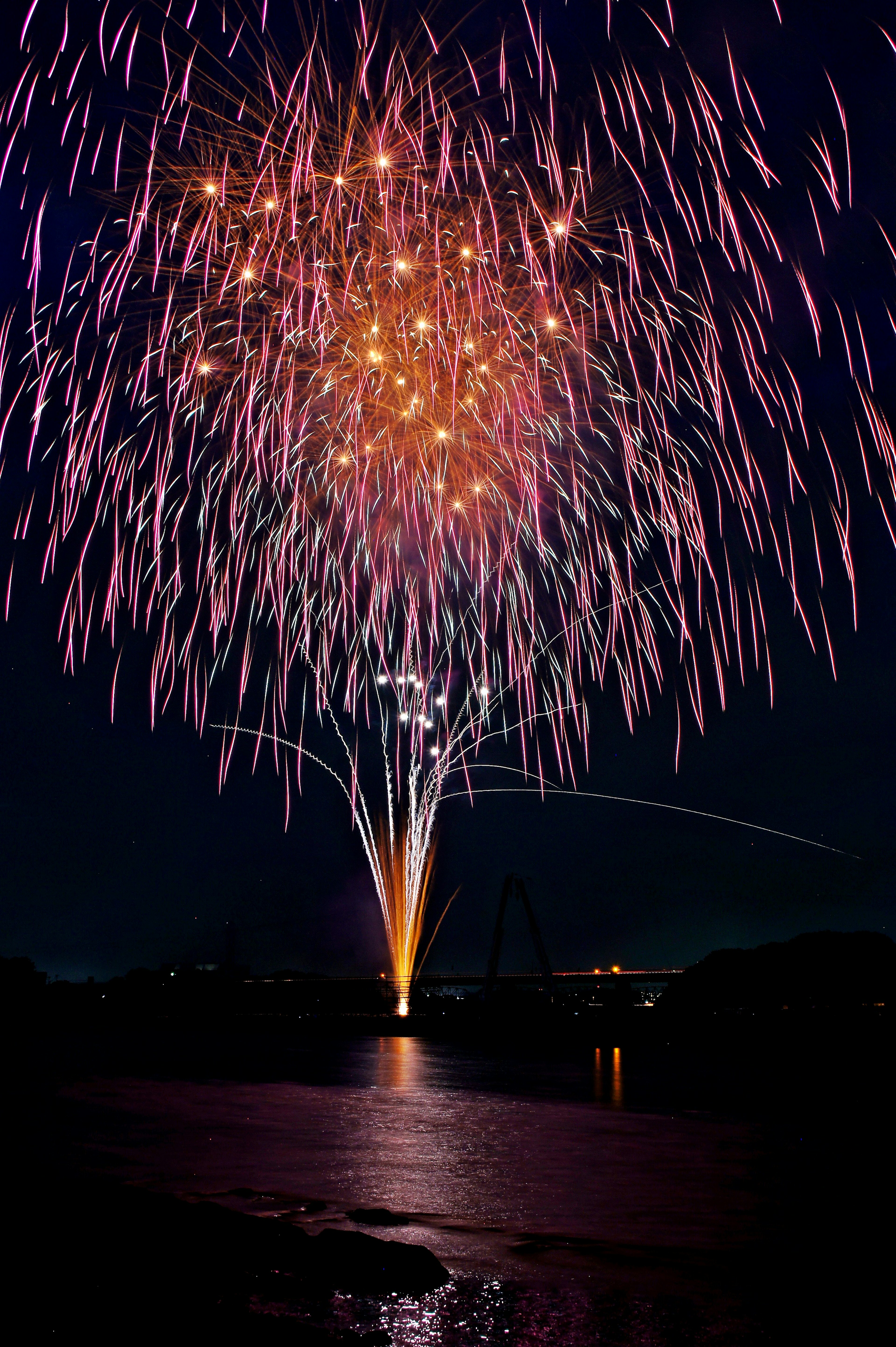 Beautiful fireworks display in the night sky with reflections on the water