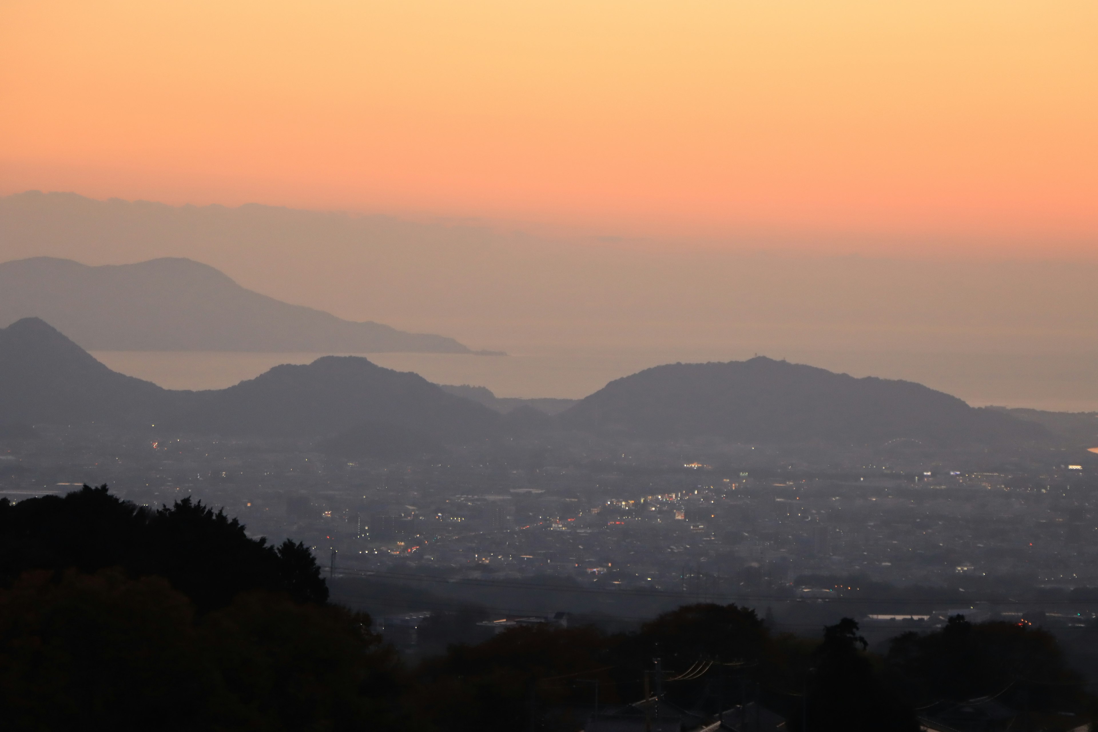 Vue panoramique des montagnes au coucher du soleil avec des lumières de la ville au loin