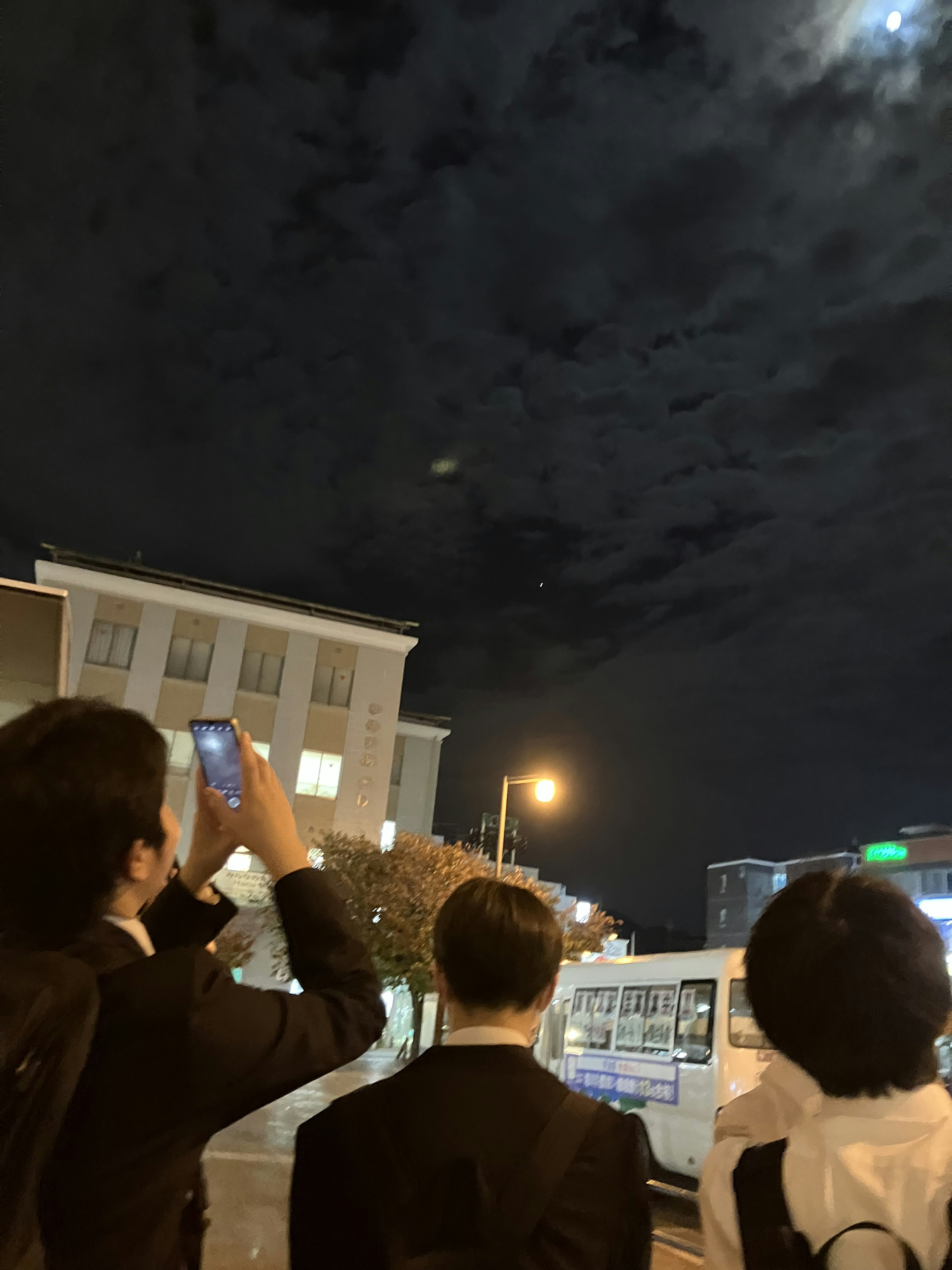 Hommes en costume regardant le ciel nocturne avec une lune brillante