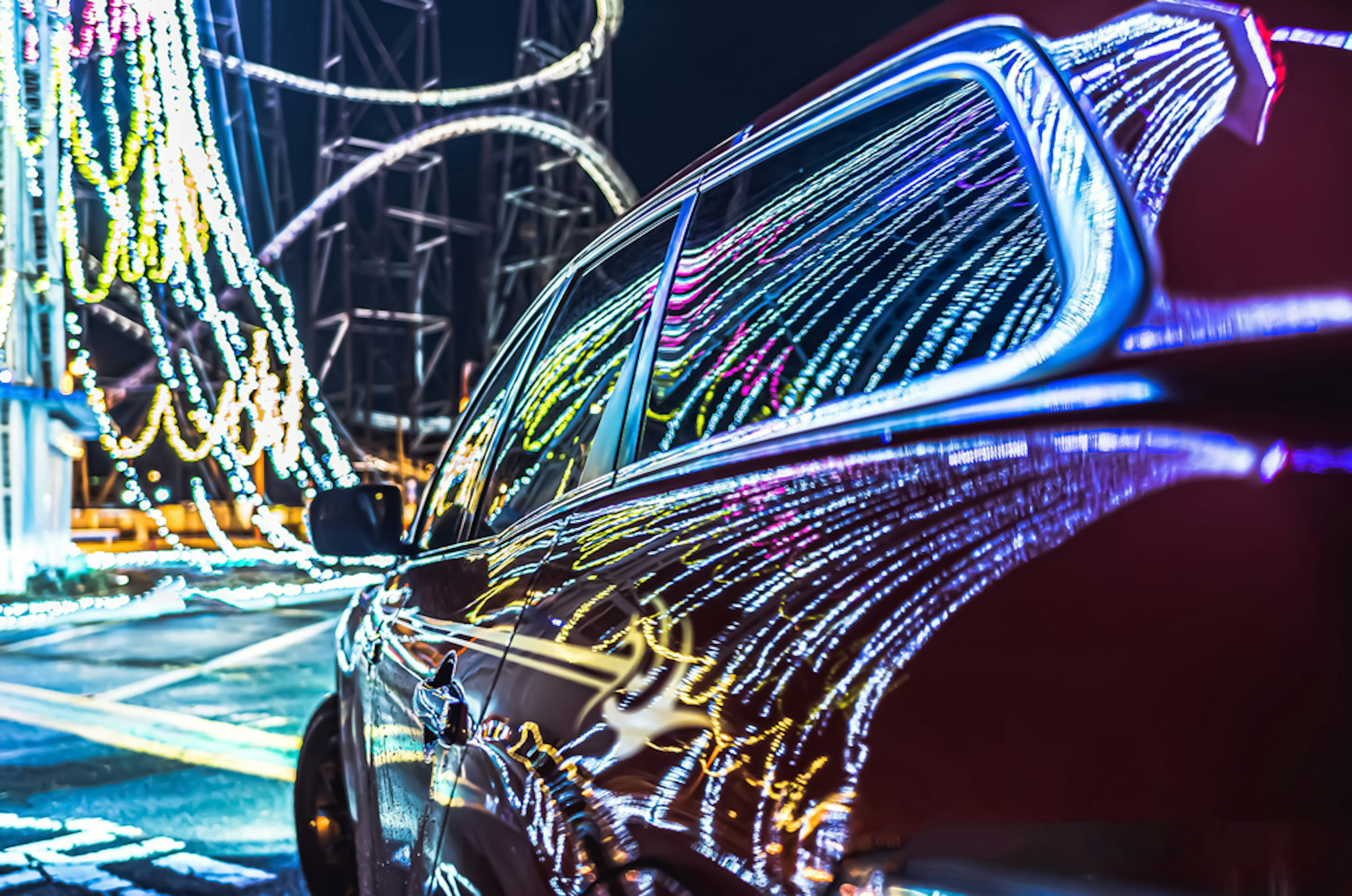 Red car reflecting colorful lights at night