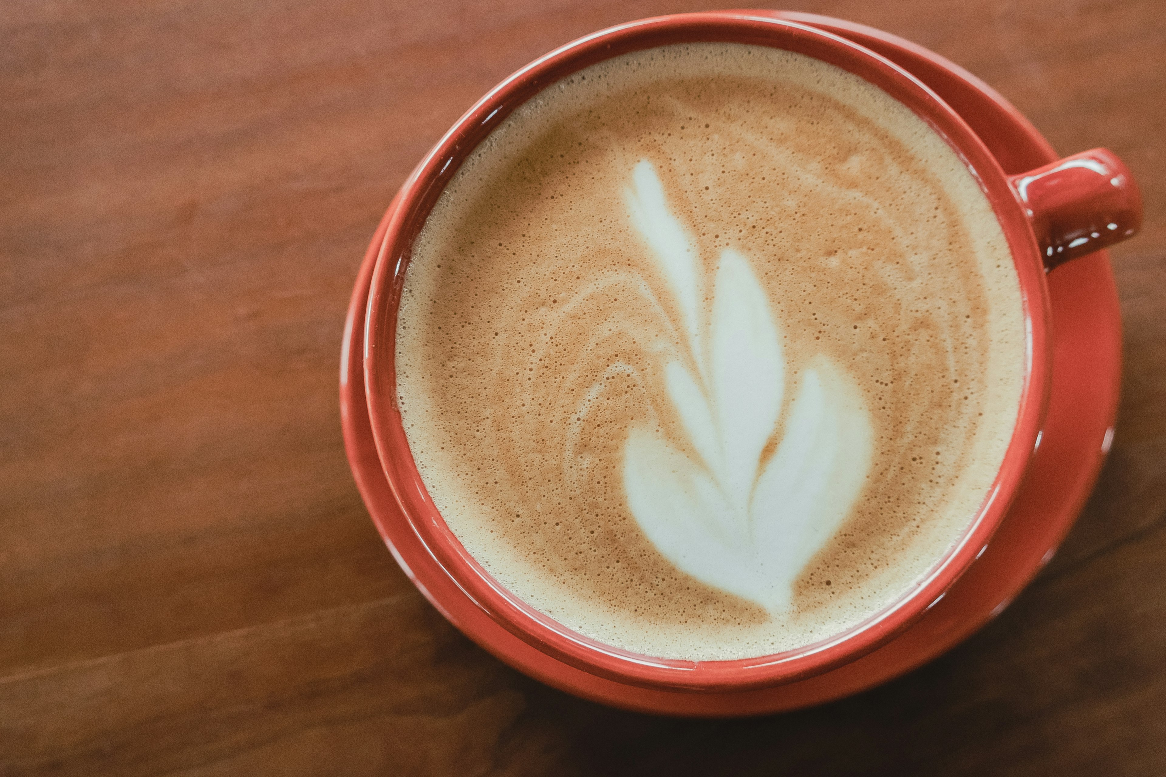 Café con leche con arte en una taza roja