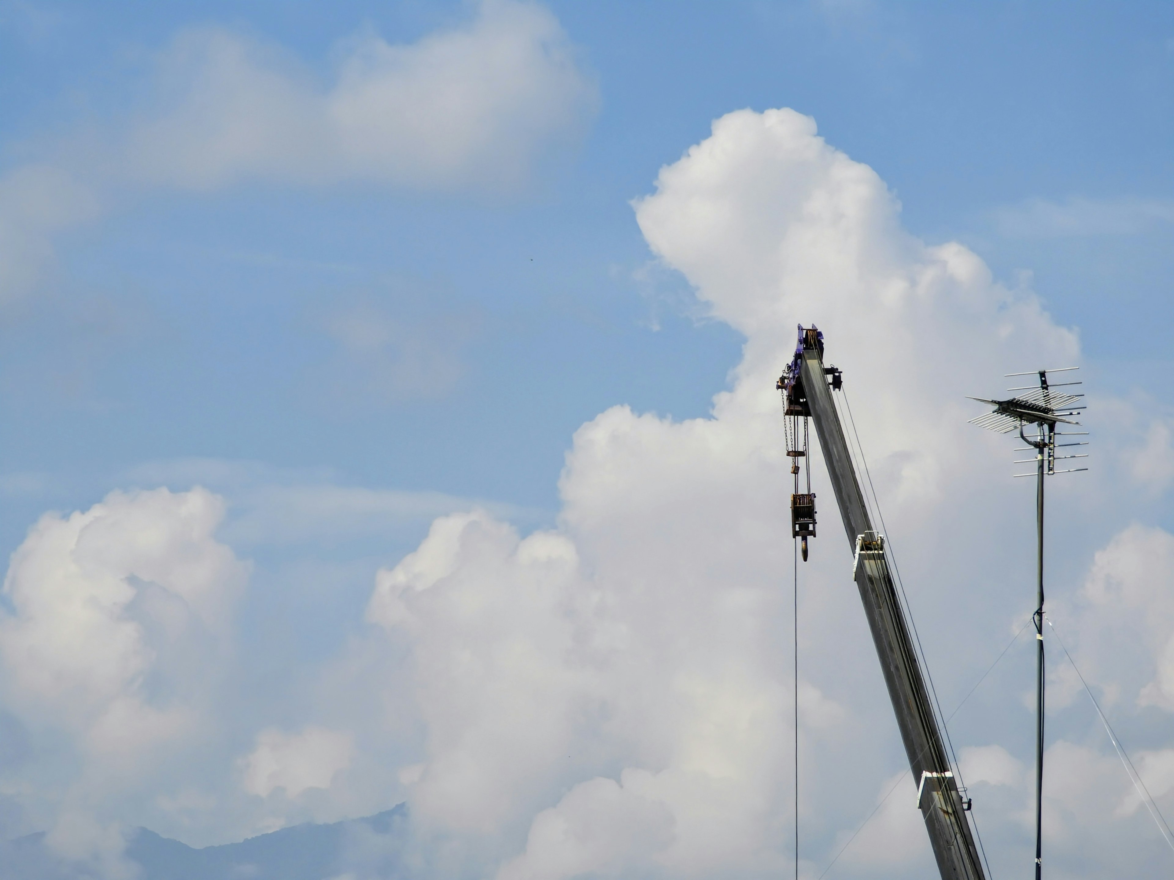 Crane against a blue sky with fluffy white clouds