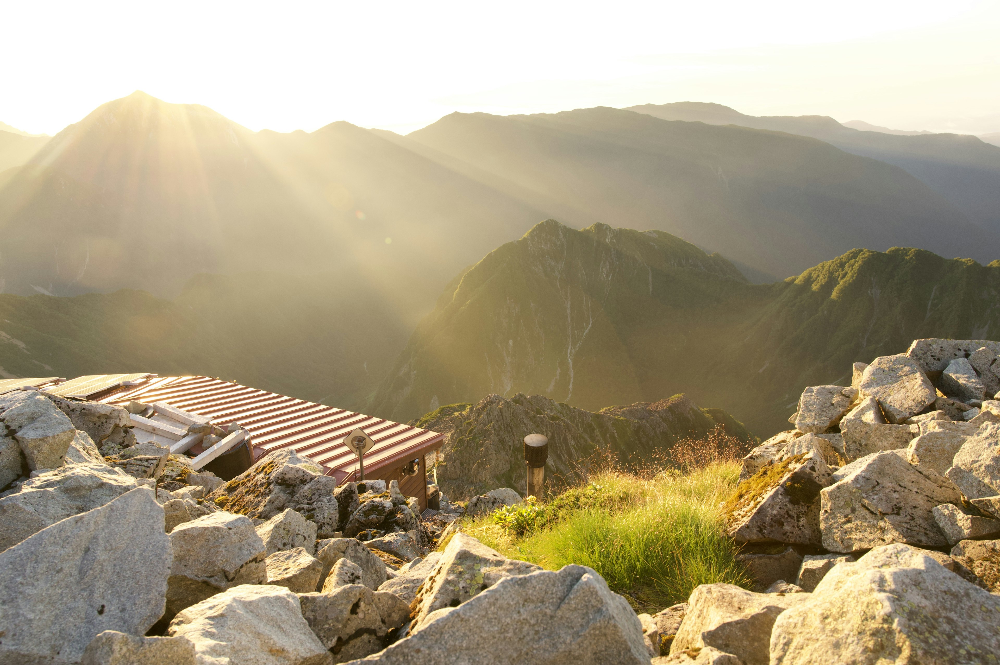 山の頂上からの美しい風景　岩と草が広がり　夕日が山々を照らす