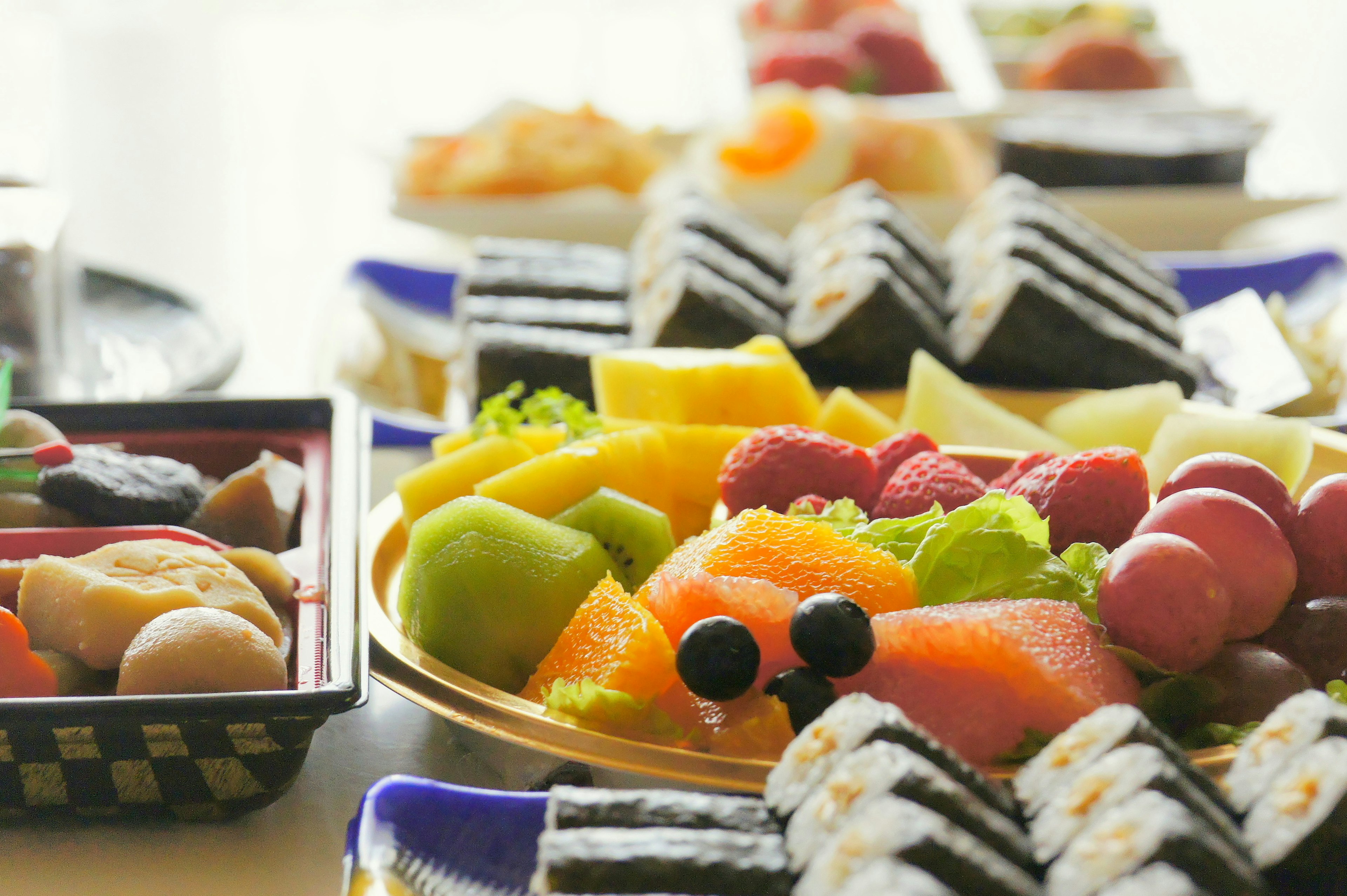 Una mesa hermosa con una colorida disposición de sushi y frutas variadas