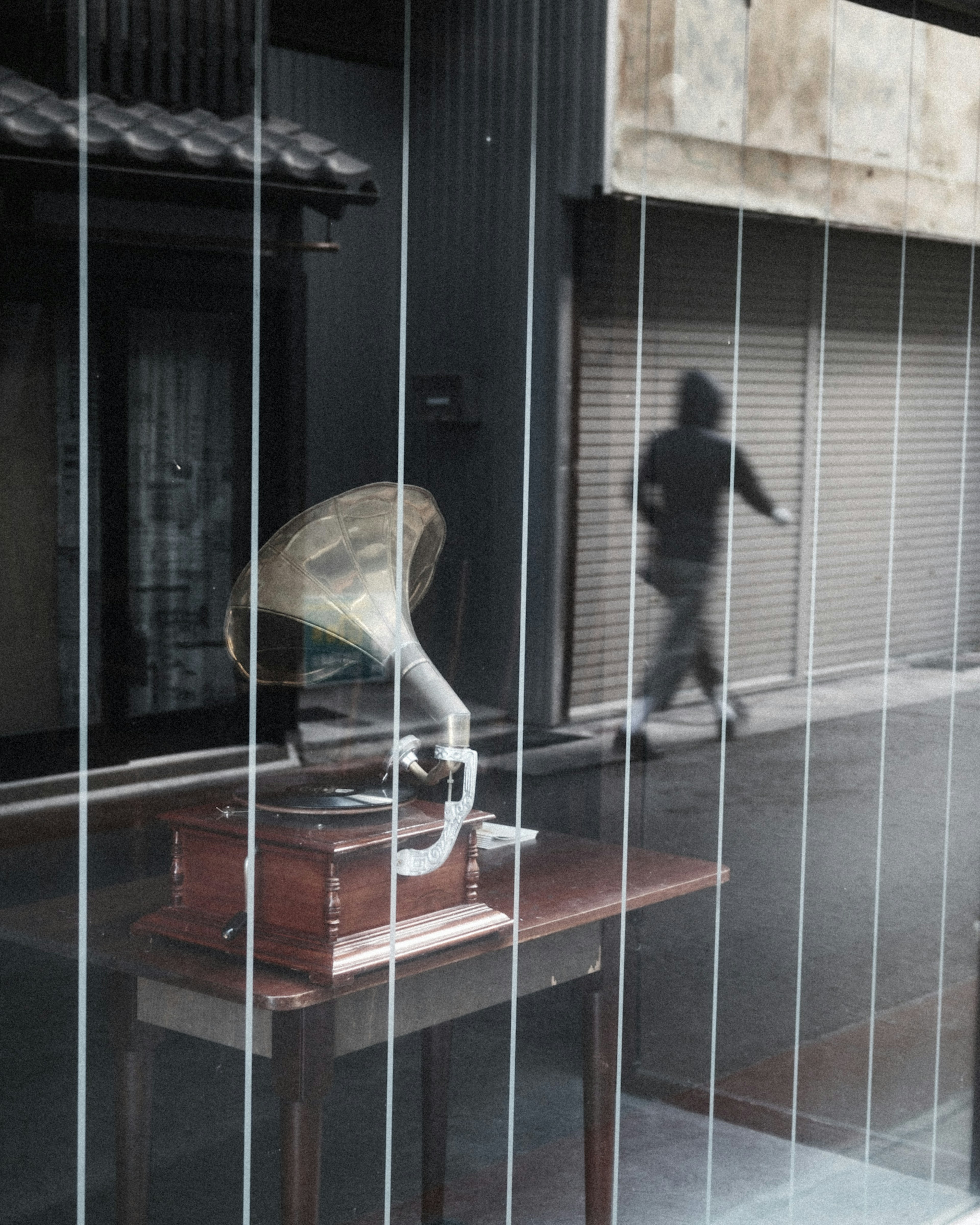 Vintage gramophone visible through glass with a figure walking outside