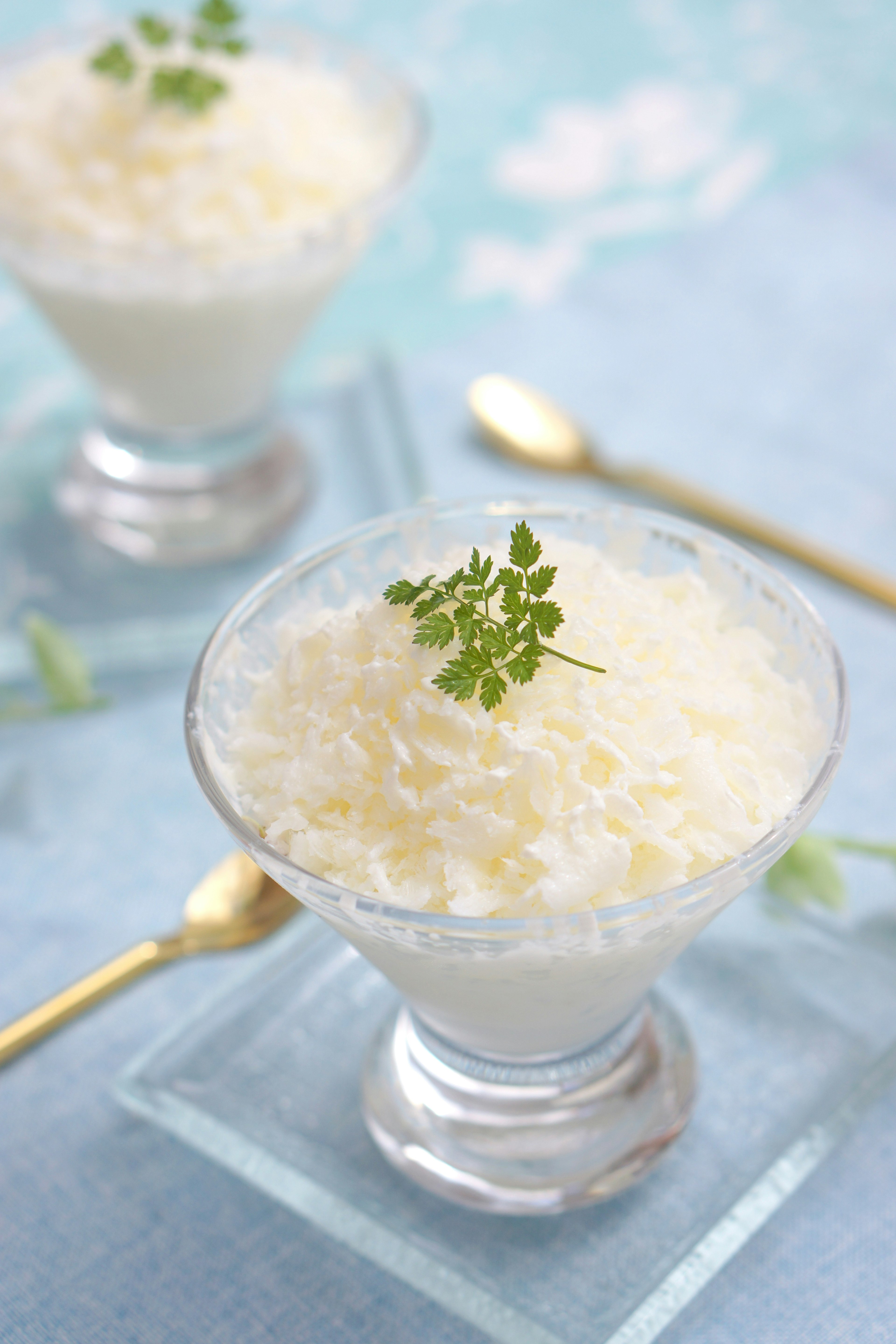 Puding putih dalam mangkuk kaca bening dihiasi dengan herbal