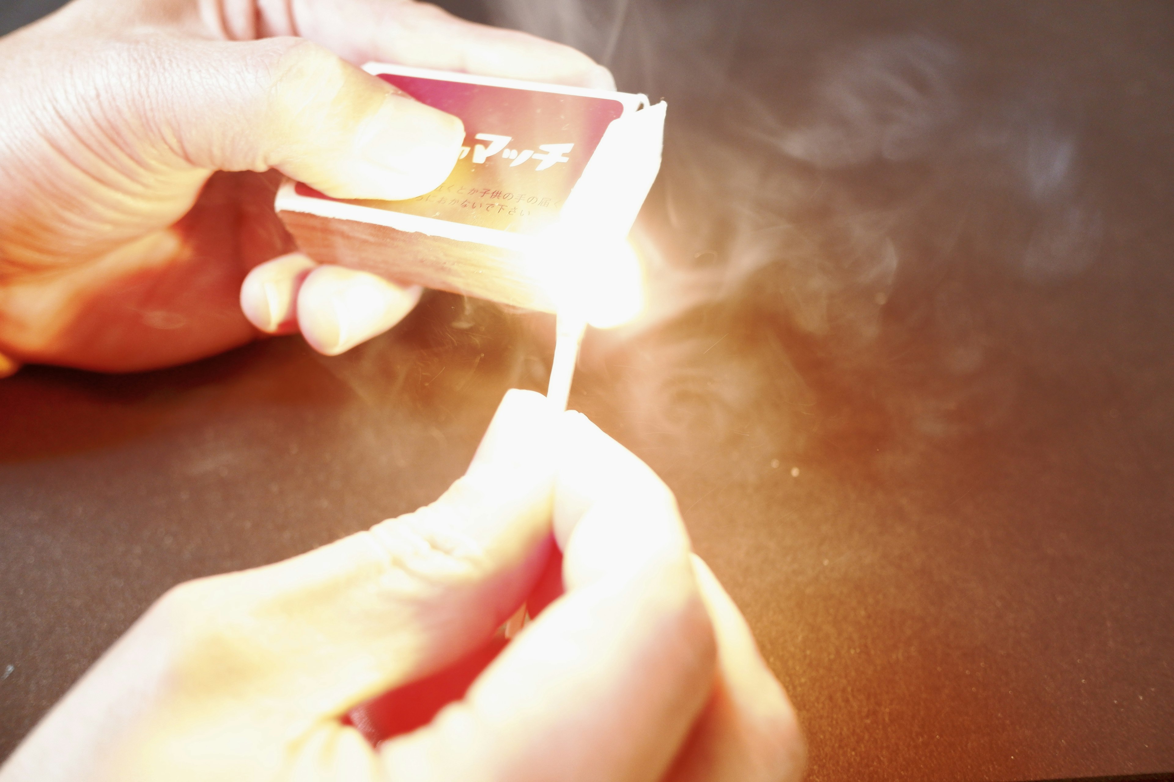 Scene of a hand lighting a match with smoke rising