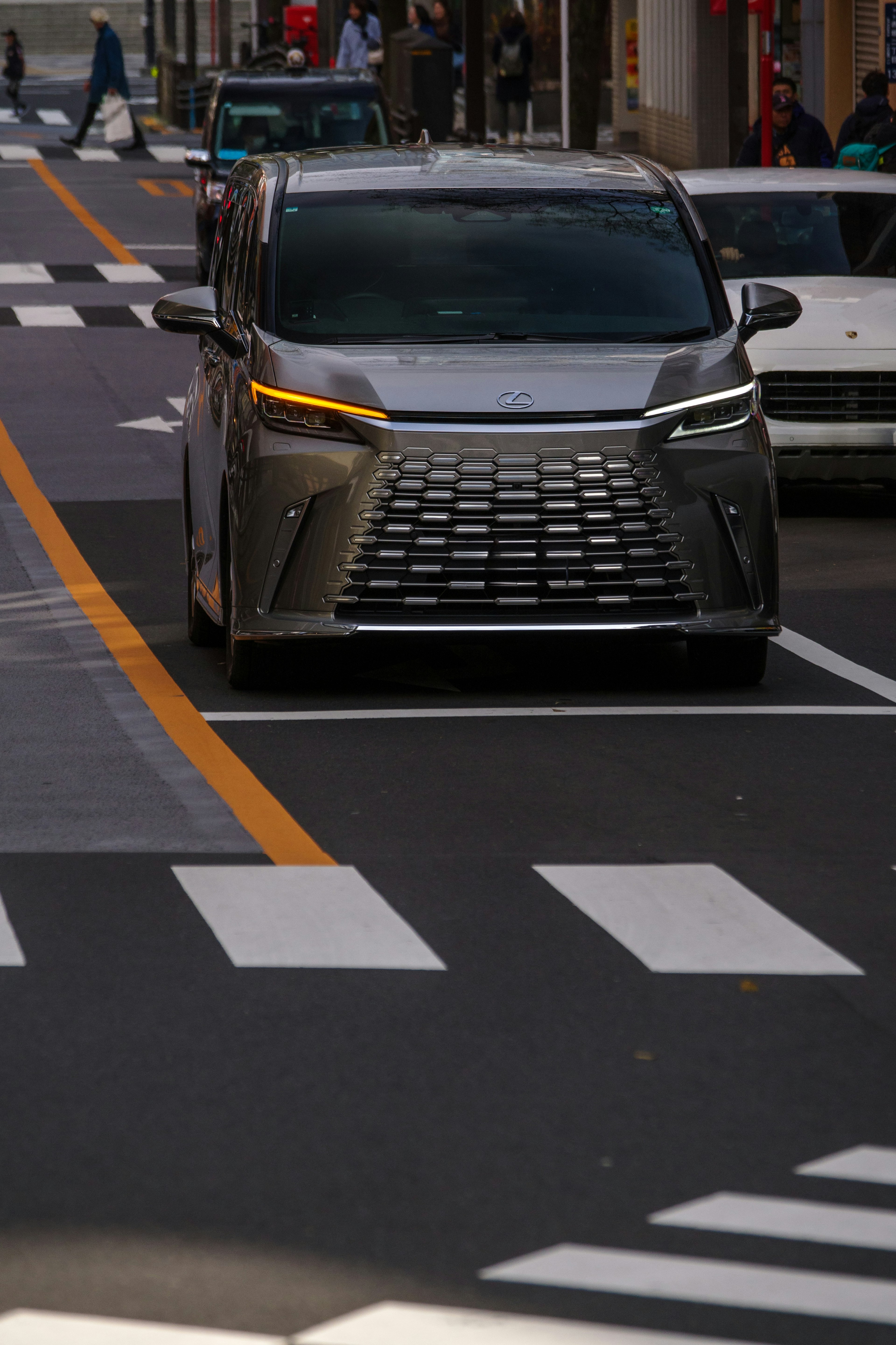 街中で走る銀色のミニバン 車線を跨いでいる