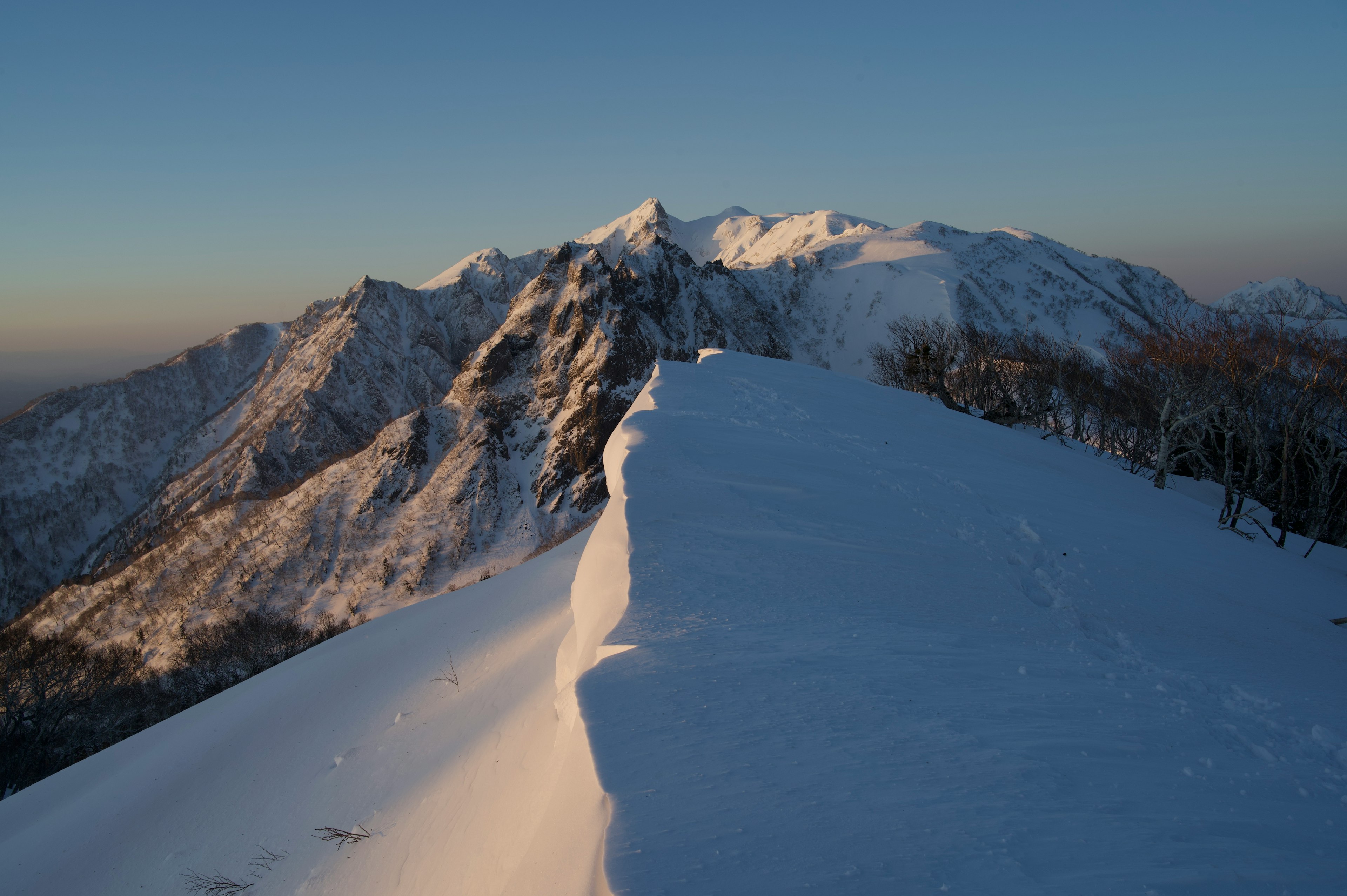 Impresionante vista de montañas cubiertas de nieve y luz del atardecer