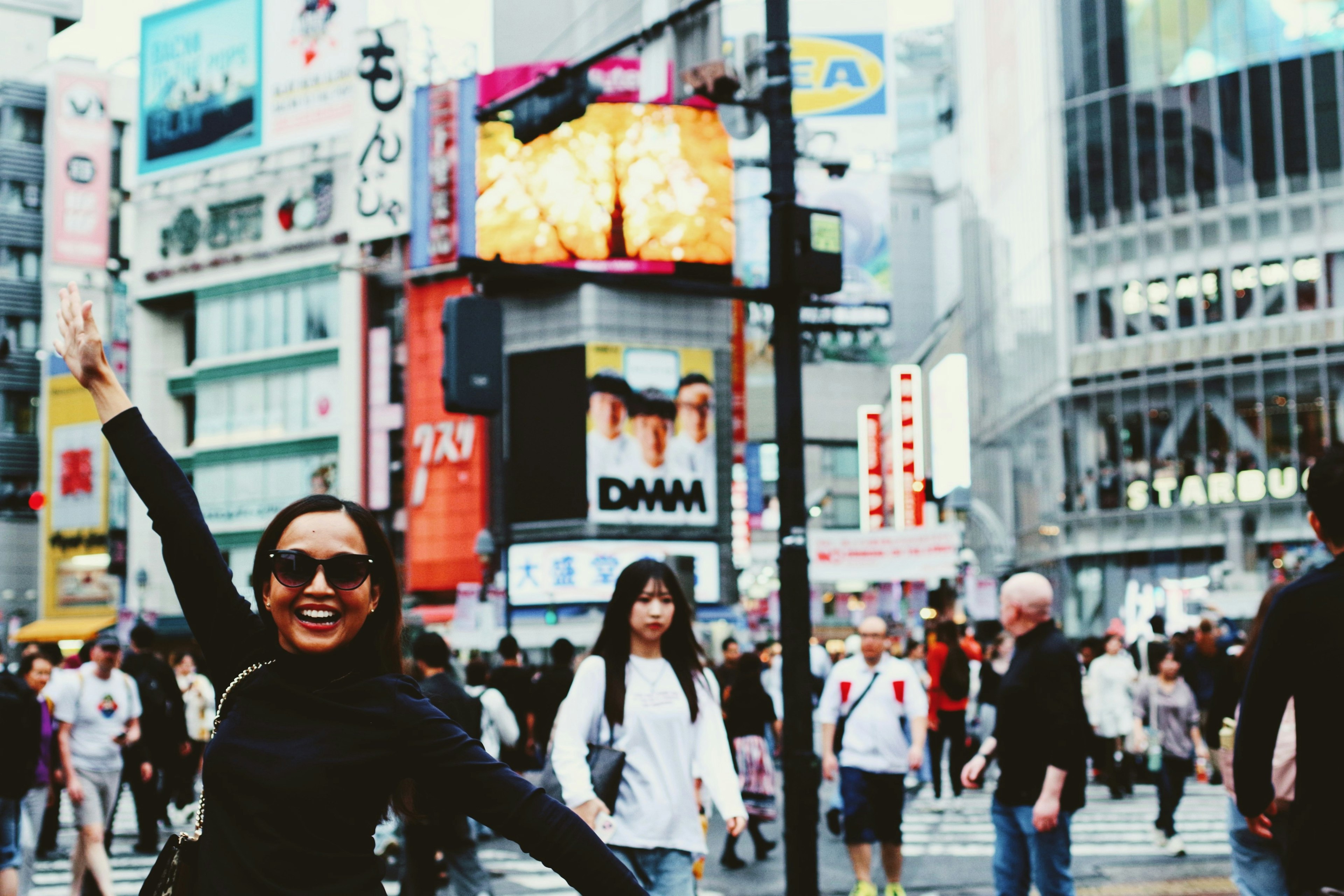 Eine lächelnde Frau am Shibuya Crossing mit einem belebten Stadtbild