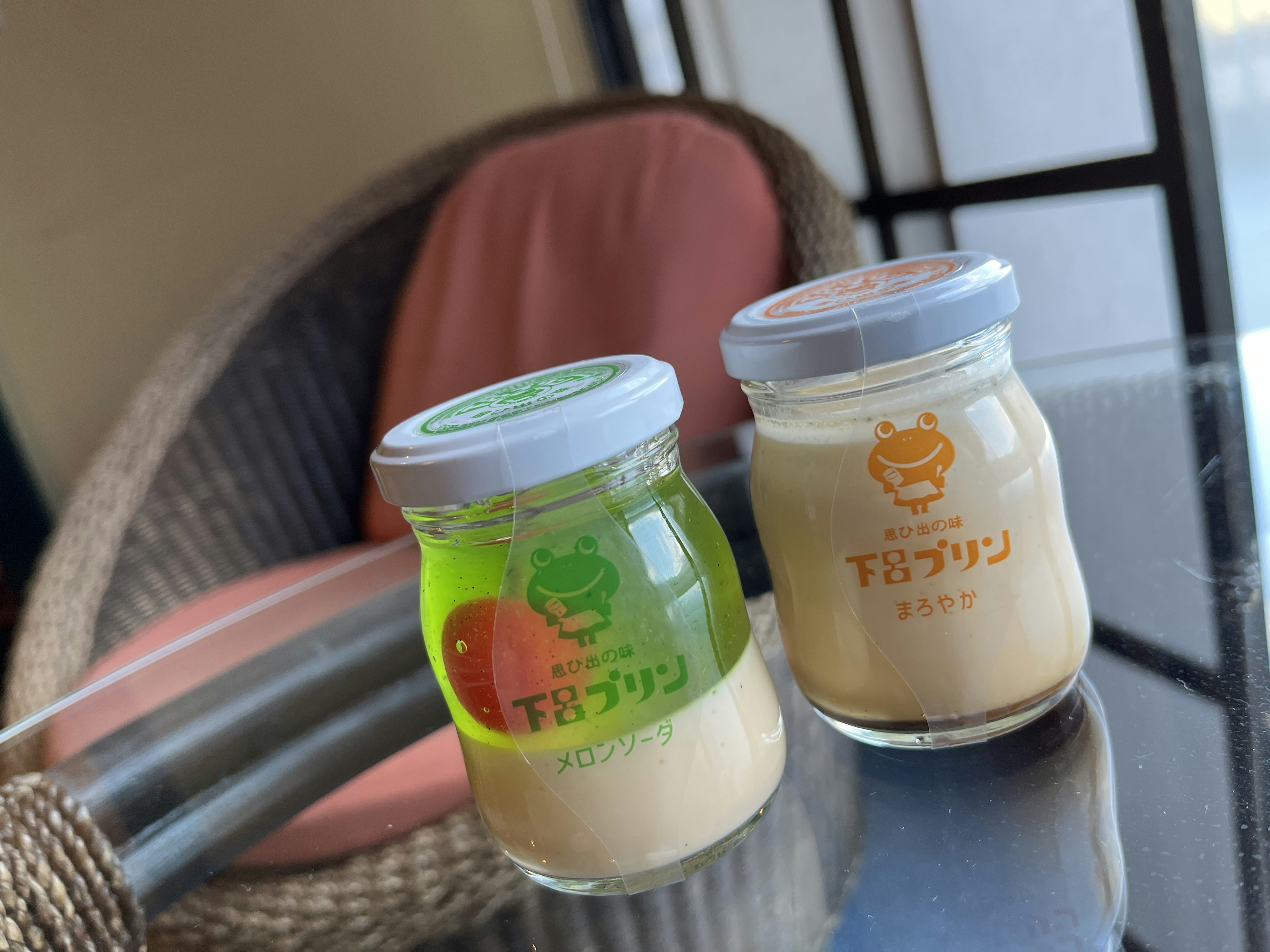 Green jelly and cream-colored pudding in glass jars placed on a table