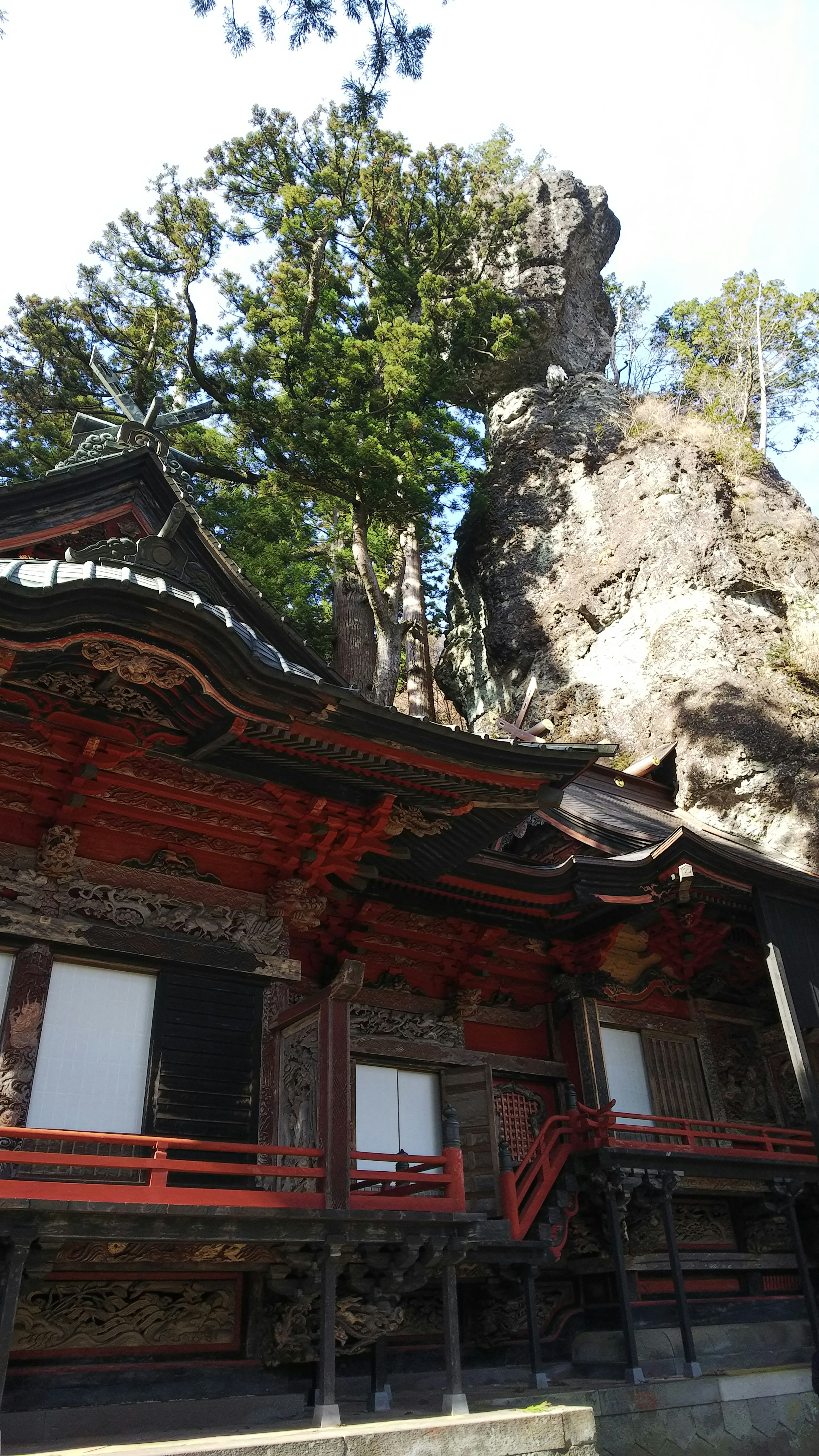 赤い縁のある伝統的な建物と巨大な岩がある風景