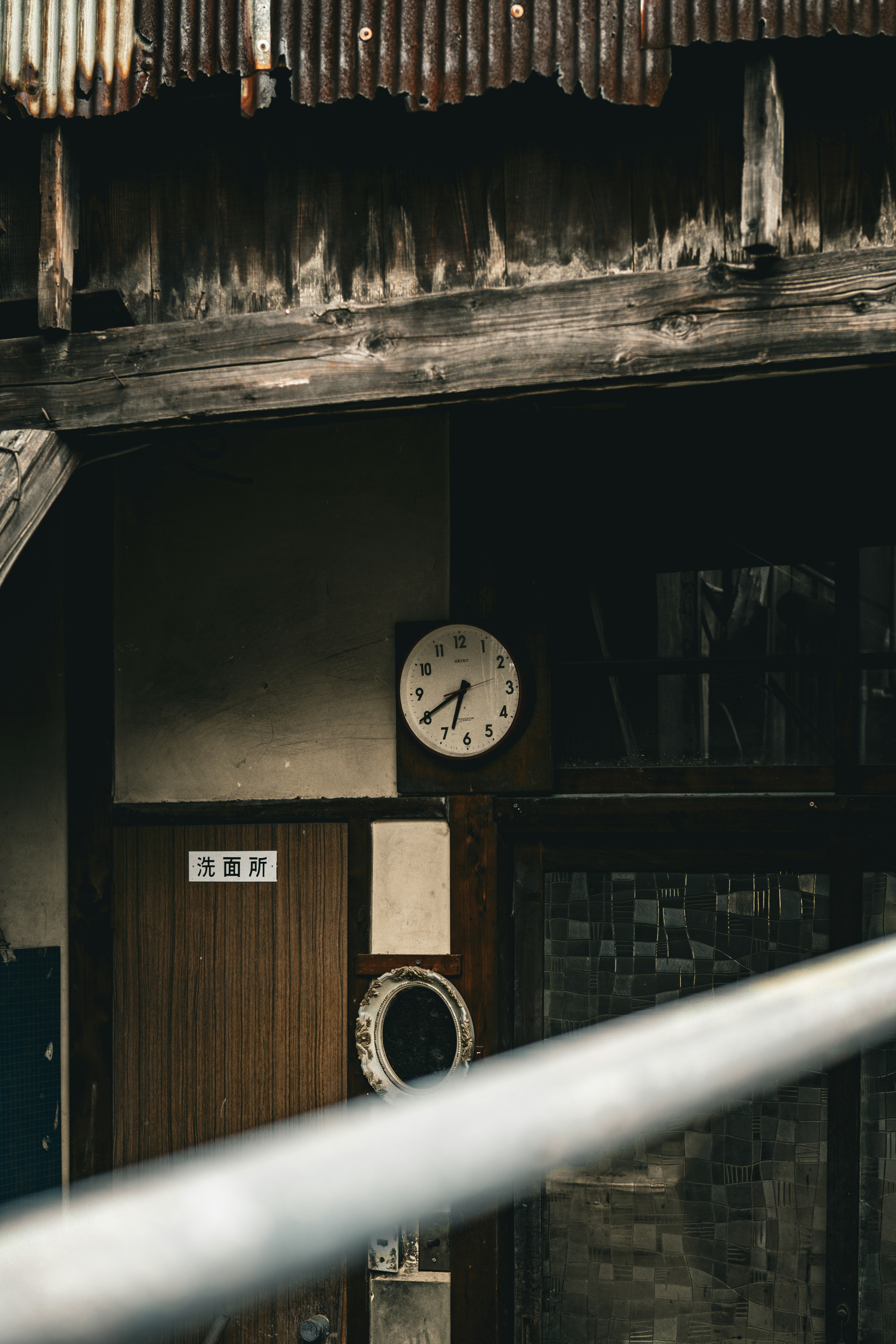 Analoge Uhr, die an der Wand eines alten Gebäudes mit Holztextur hängt